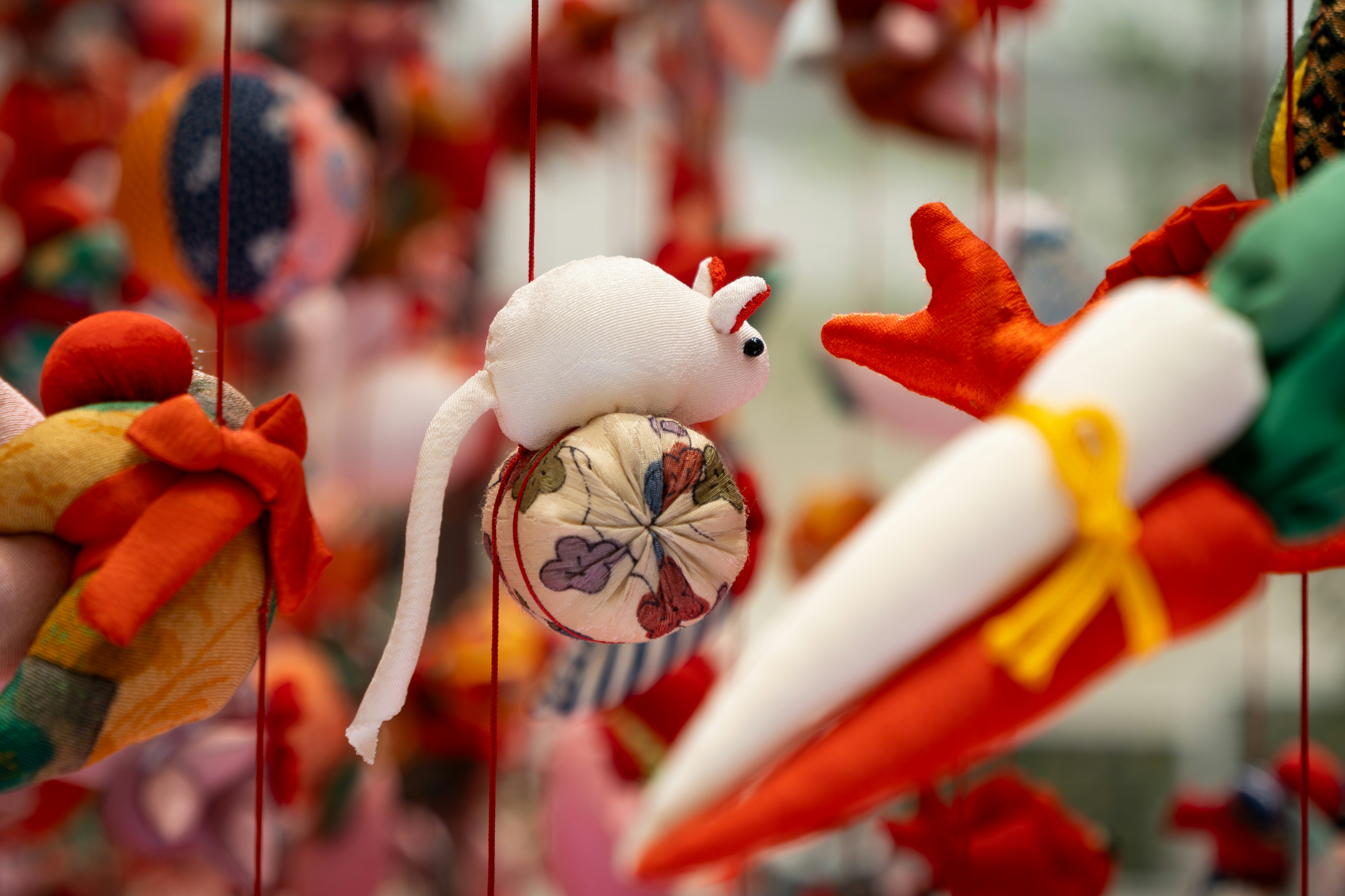 A white plush mouse stands out among colorful ornaments