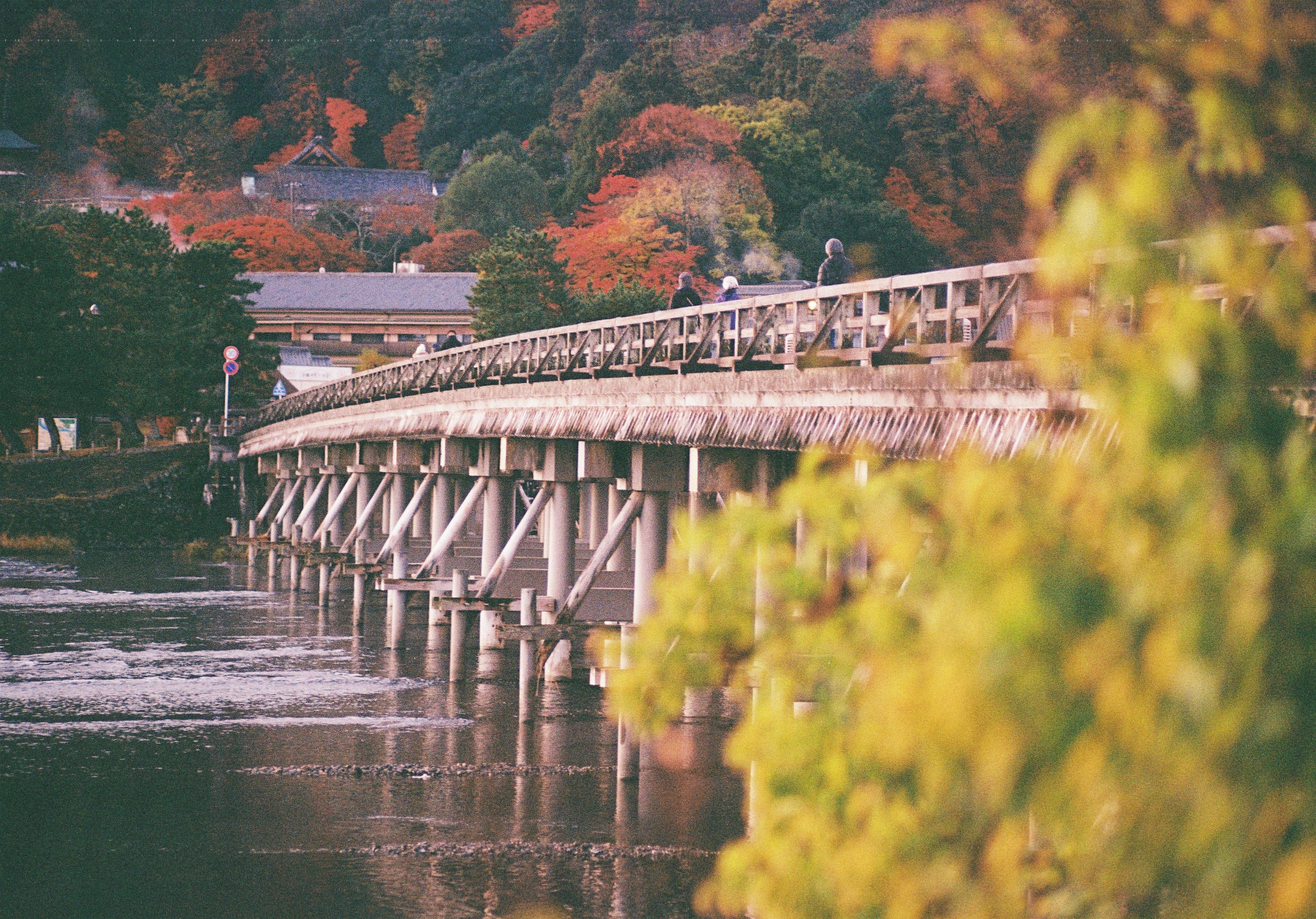 Long pont en bois sur une rivière entourée de feuillage d'automne