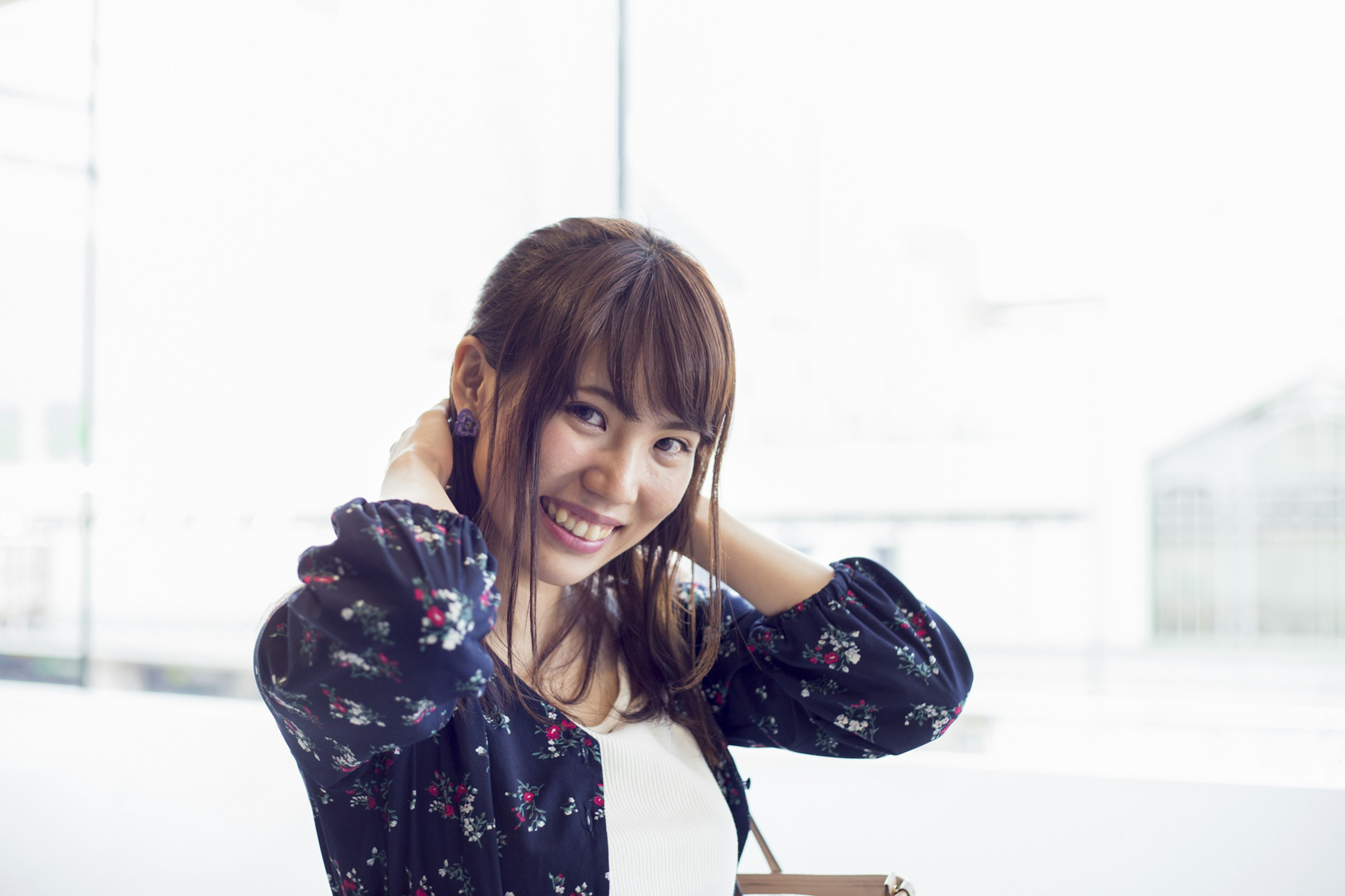 Smiling woman adjusting her hair near a bright window