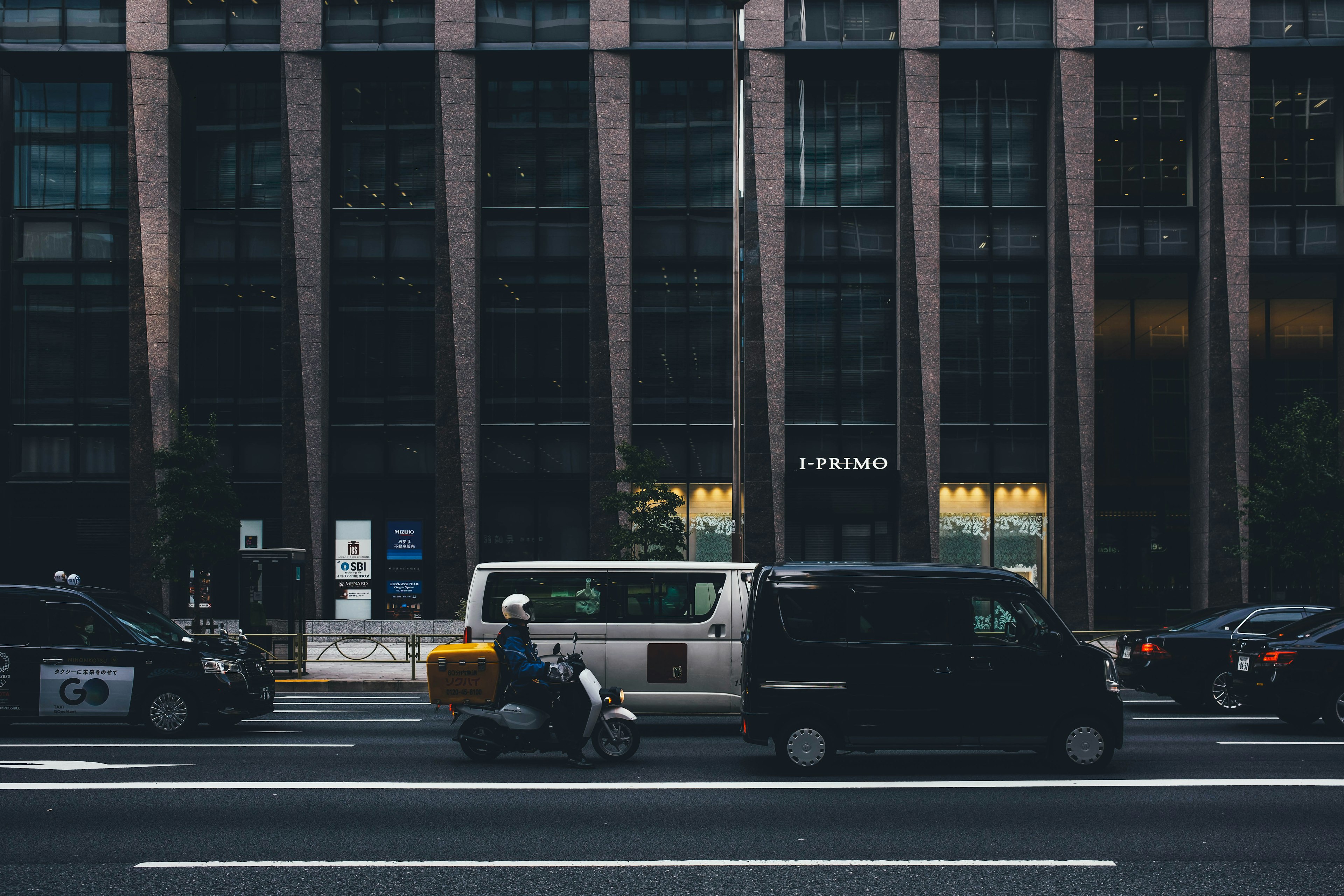 城市道路上騎摩托車的送貨員與多種車輛的場景