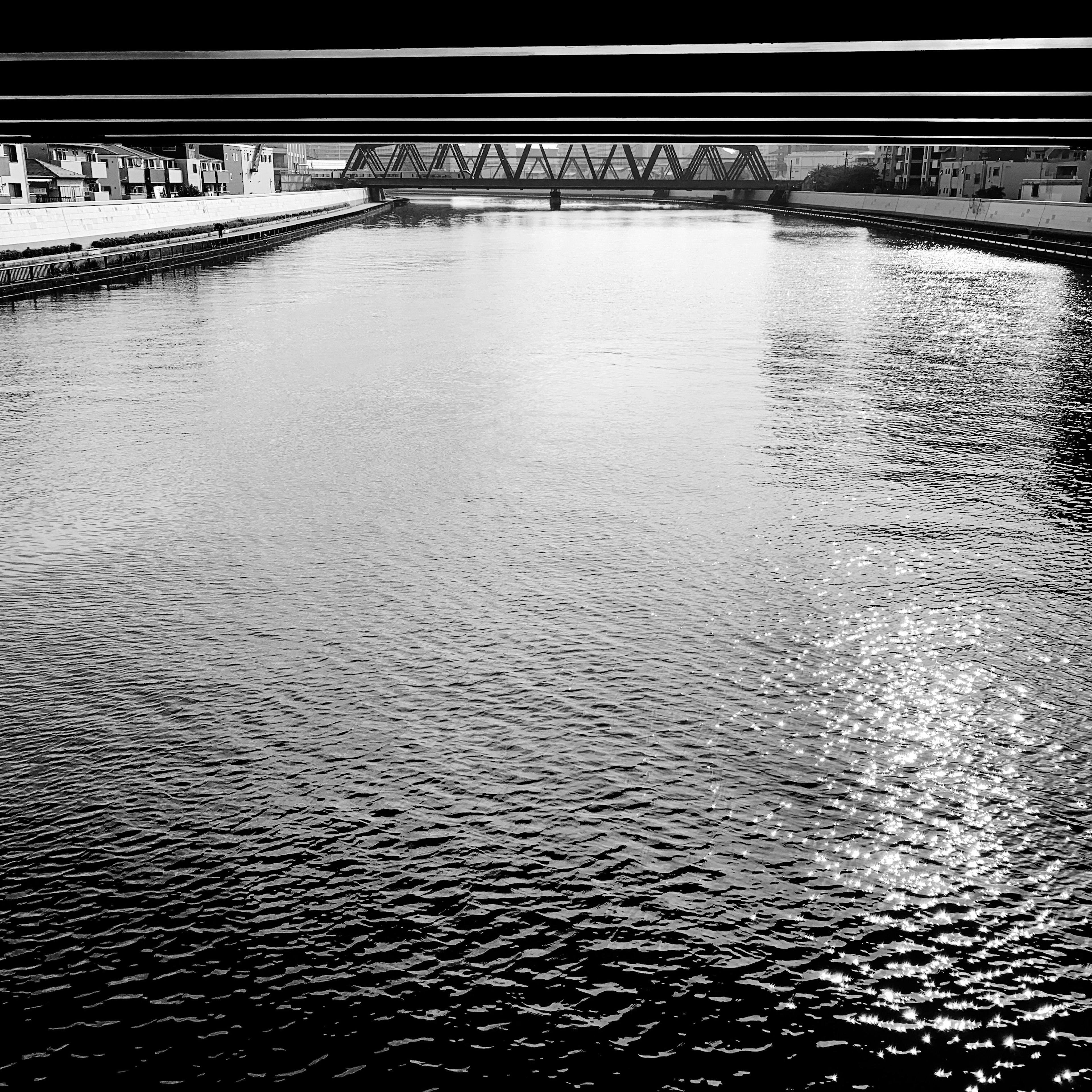 Scène de rivière en noir et blanc Vue sous un pont Reflets de lumière sur la surface de l'eau