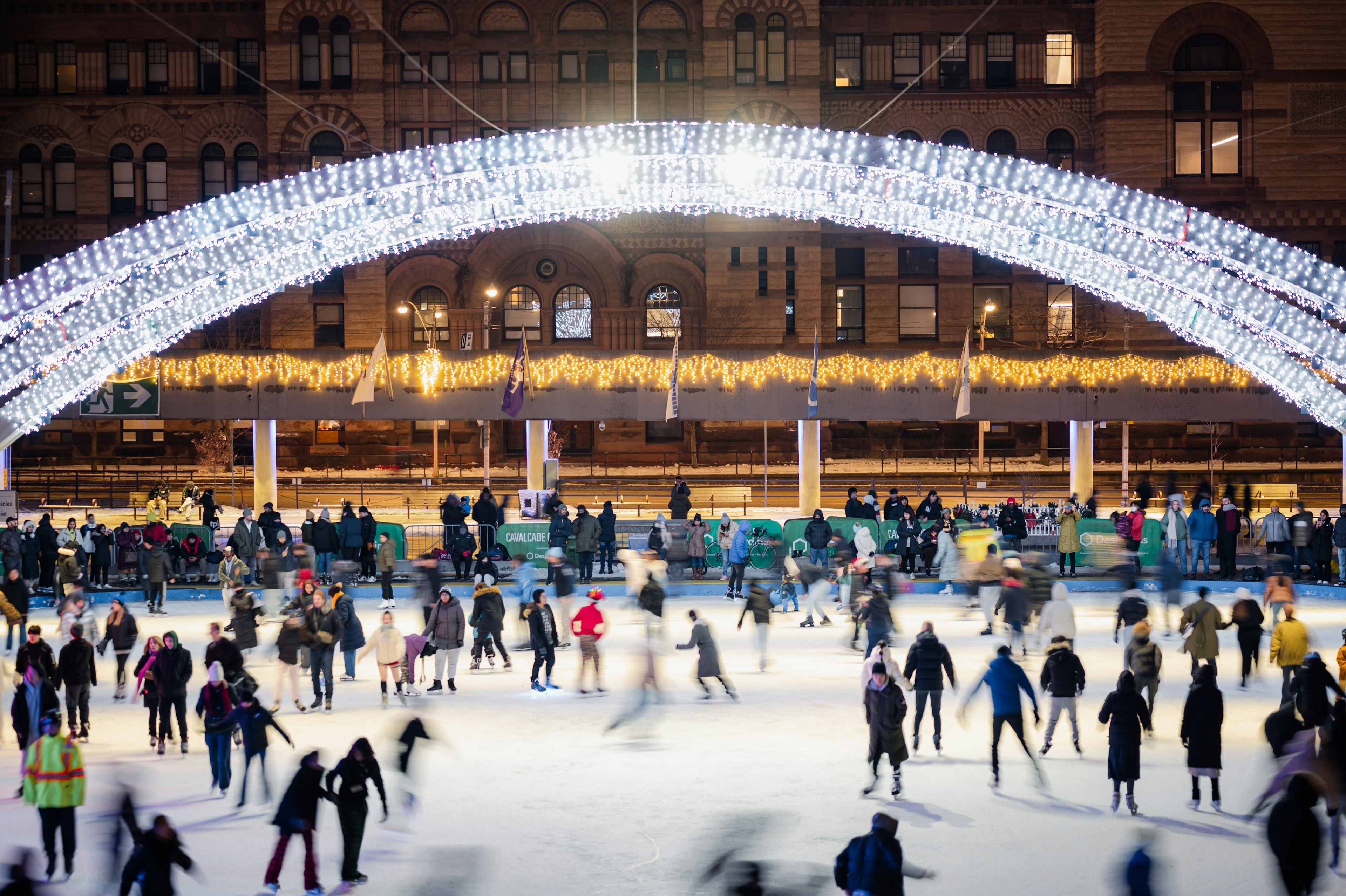 People skating on a night ice rink with a beautiful light arch overhead