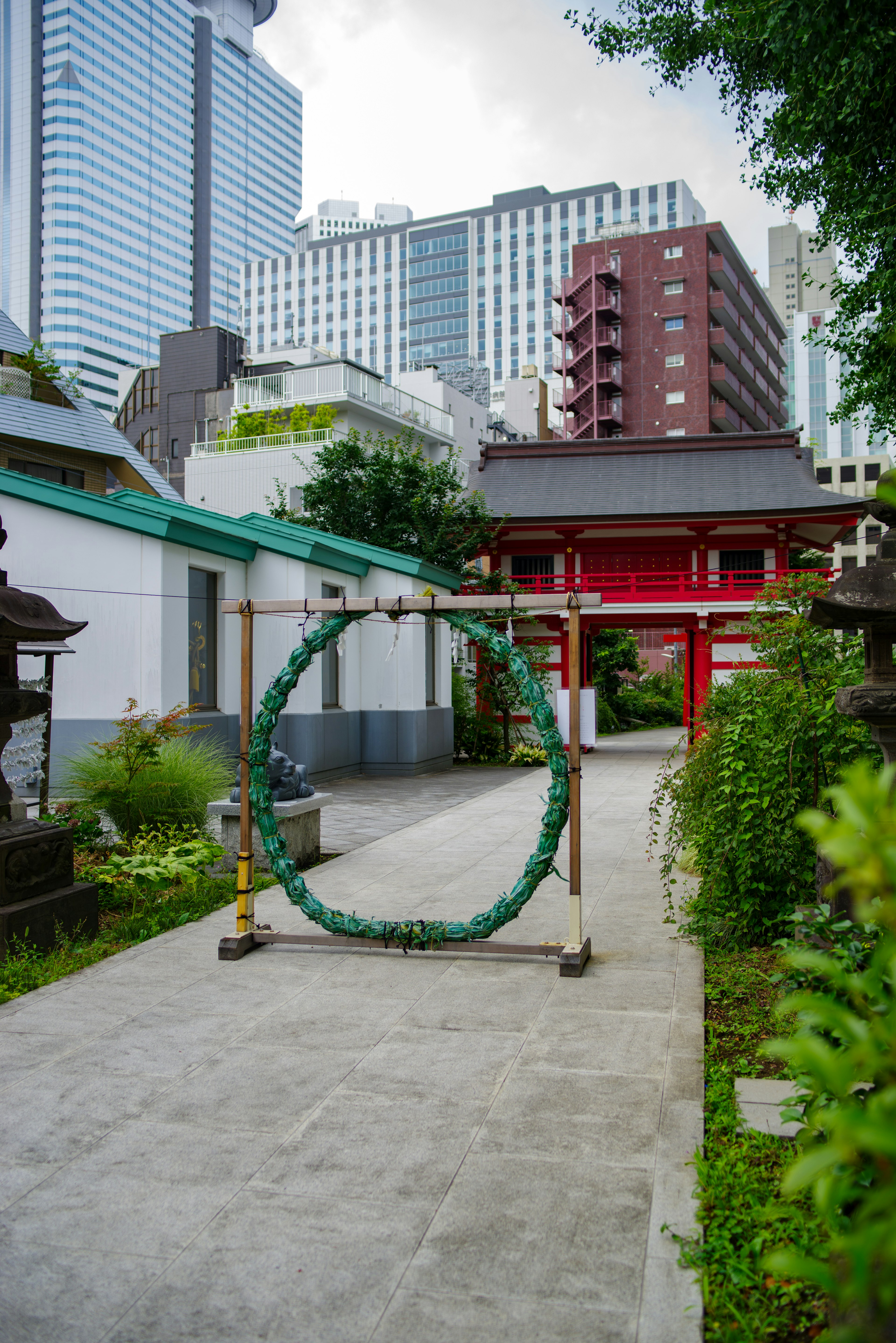 Green ring at the entrance of an urban shrine with skyscrapers in the background