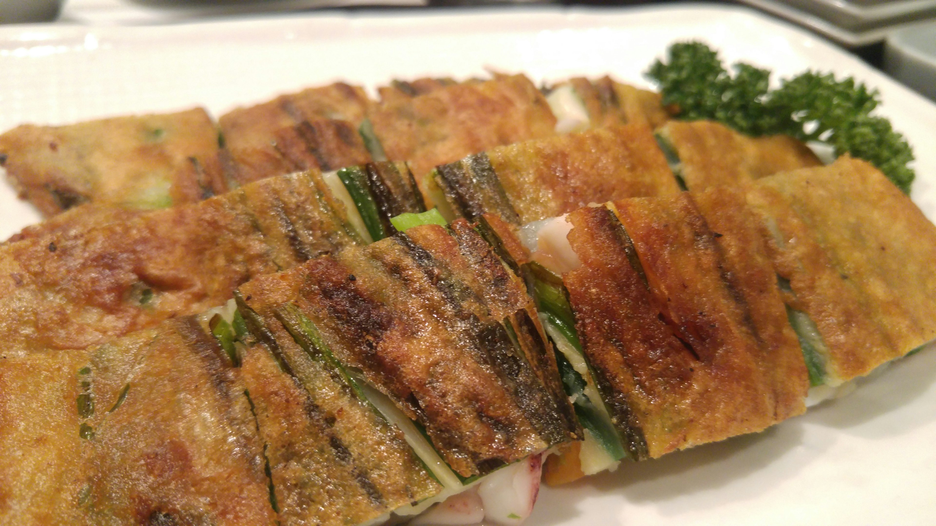 Plated crispy spring rolls showcasing layers of fresh vegetables with a garnish of parsley