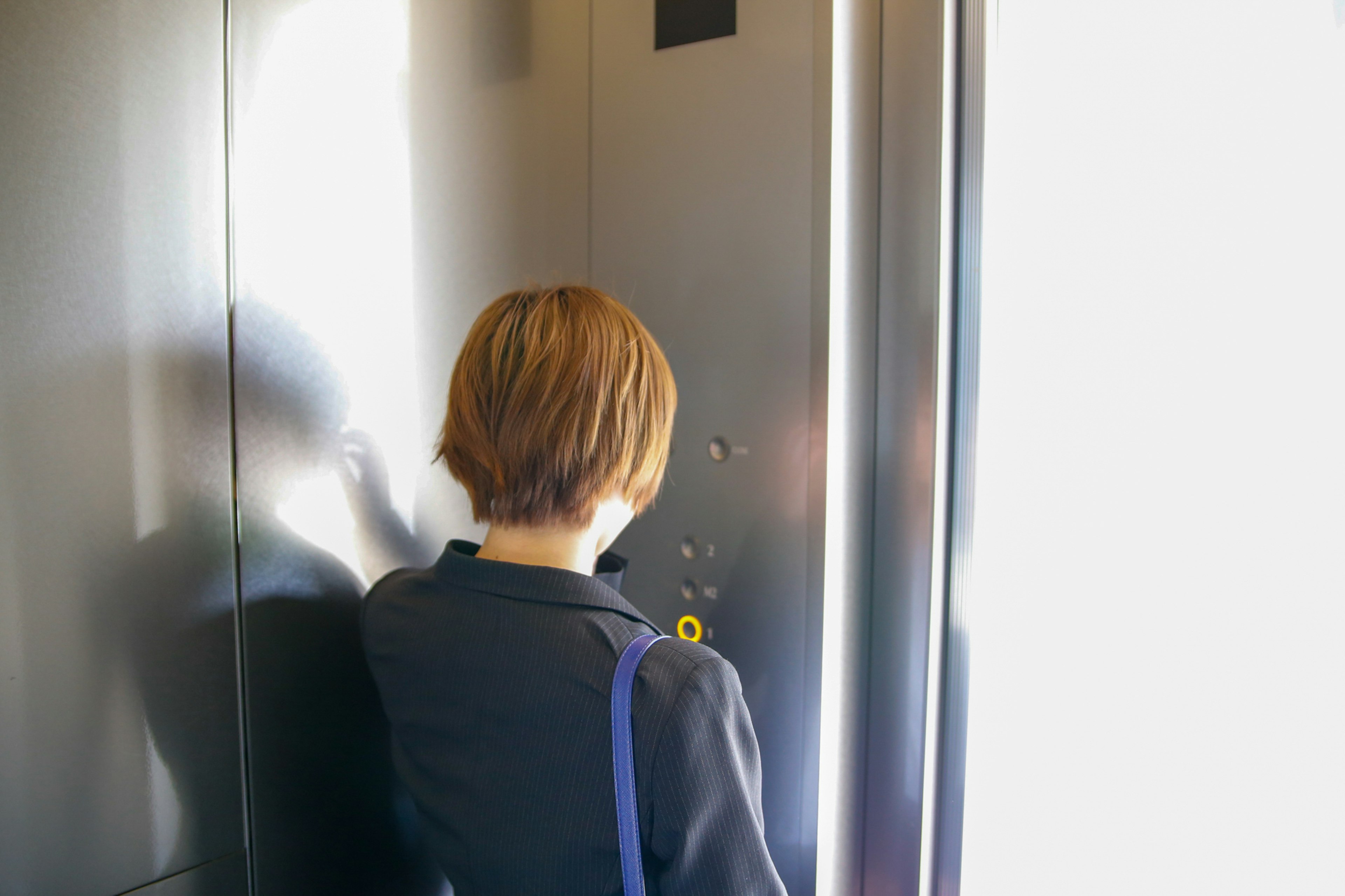 Vue arrière d'une femme dans un ascenseur appuyant sur des boutons