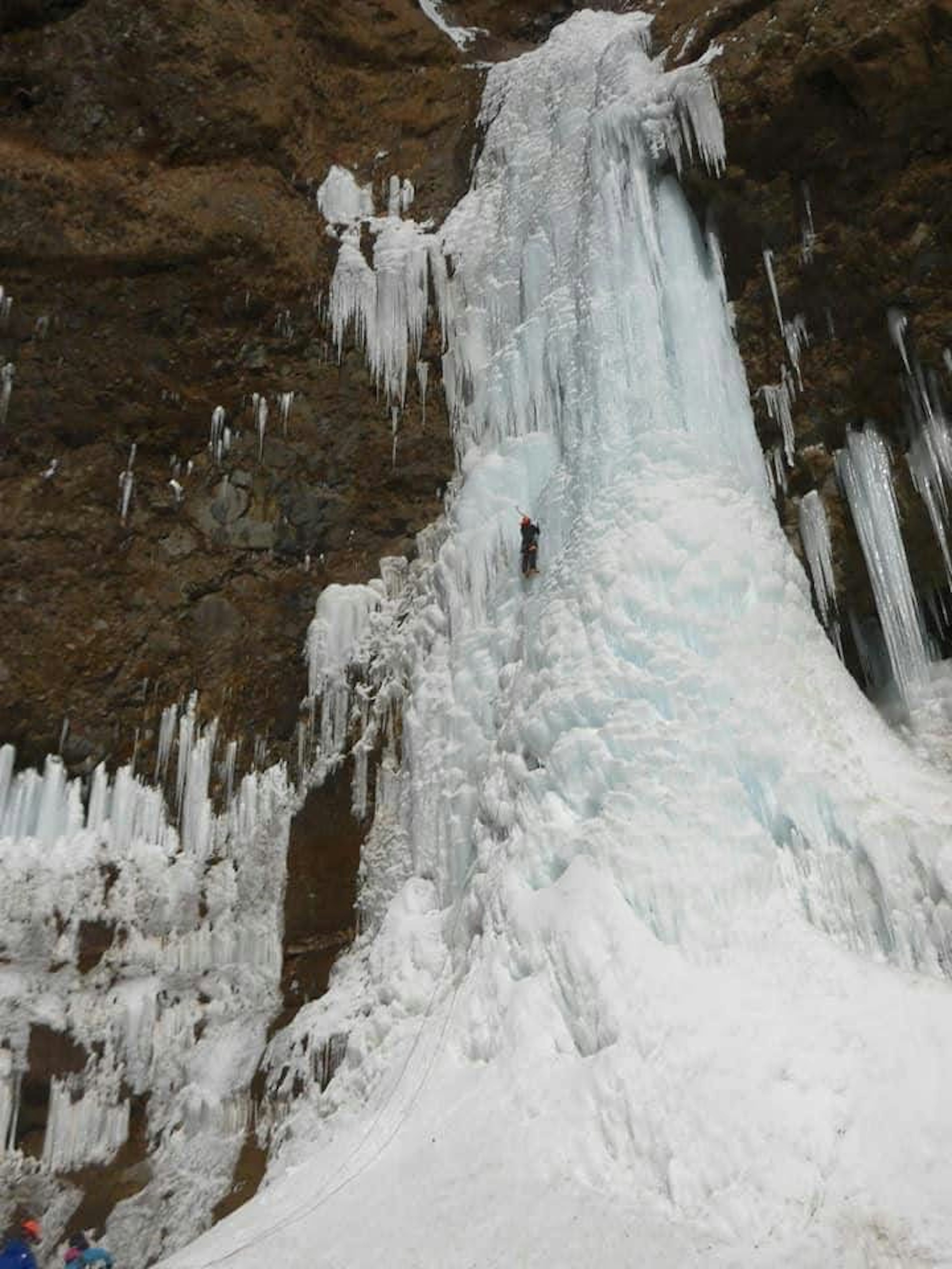 A frozen waterfall with an ice climber scaling the icy surface