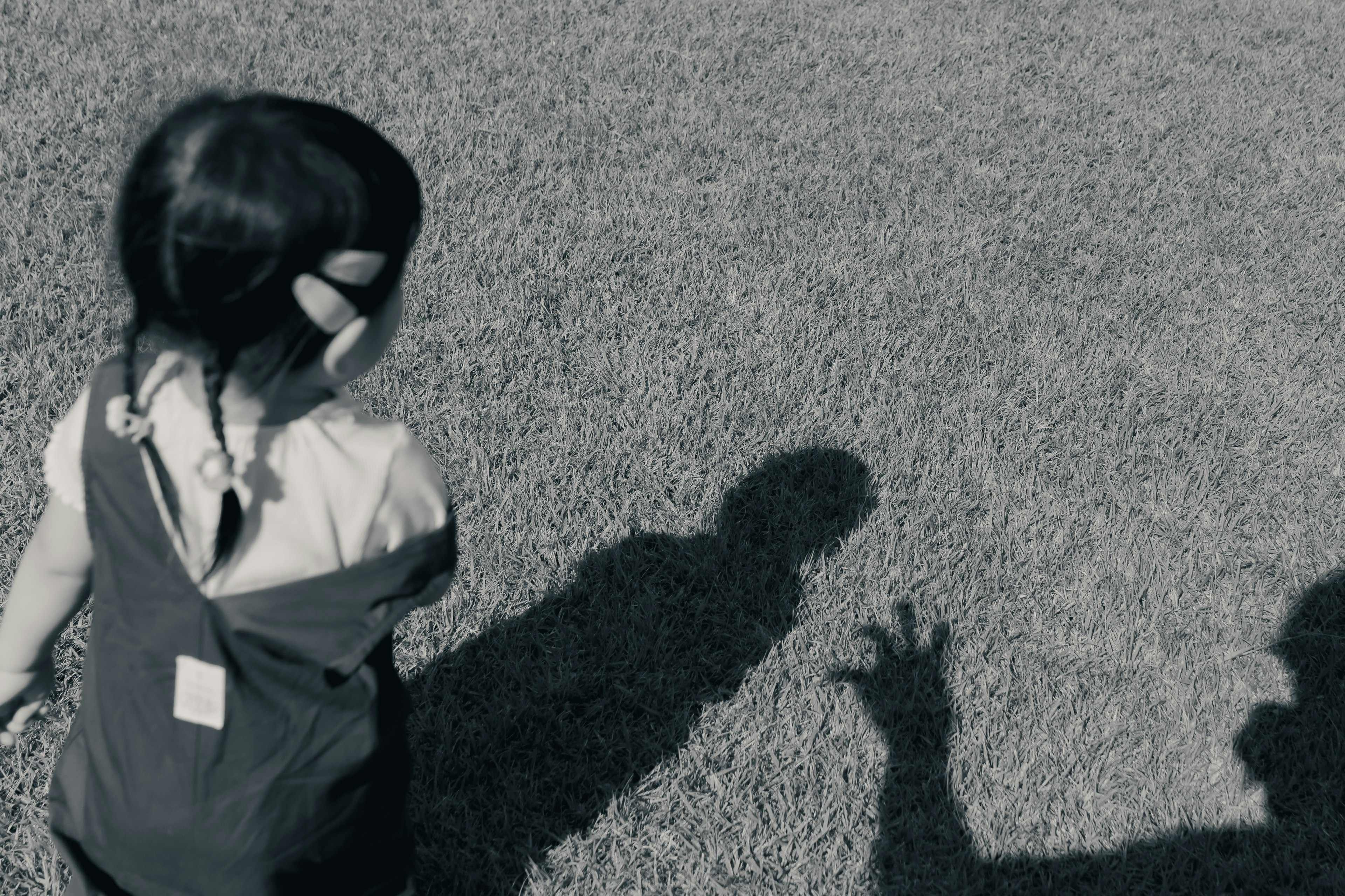 Enfant marchant sur l'herbe avec une ombre qui s'étend