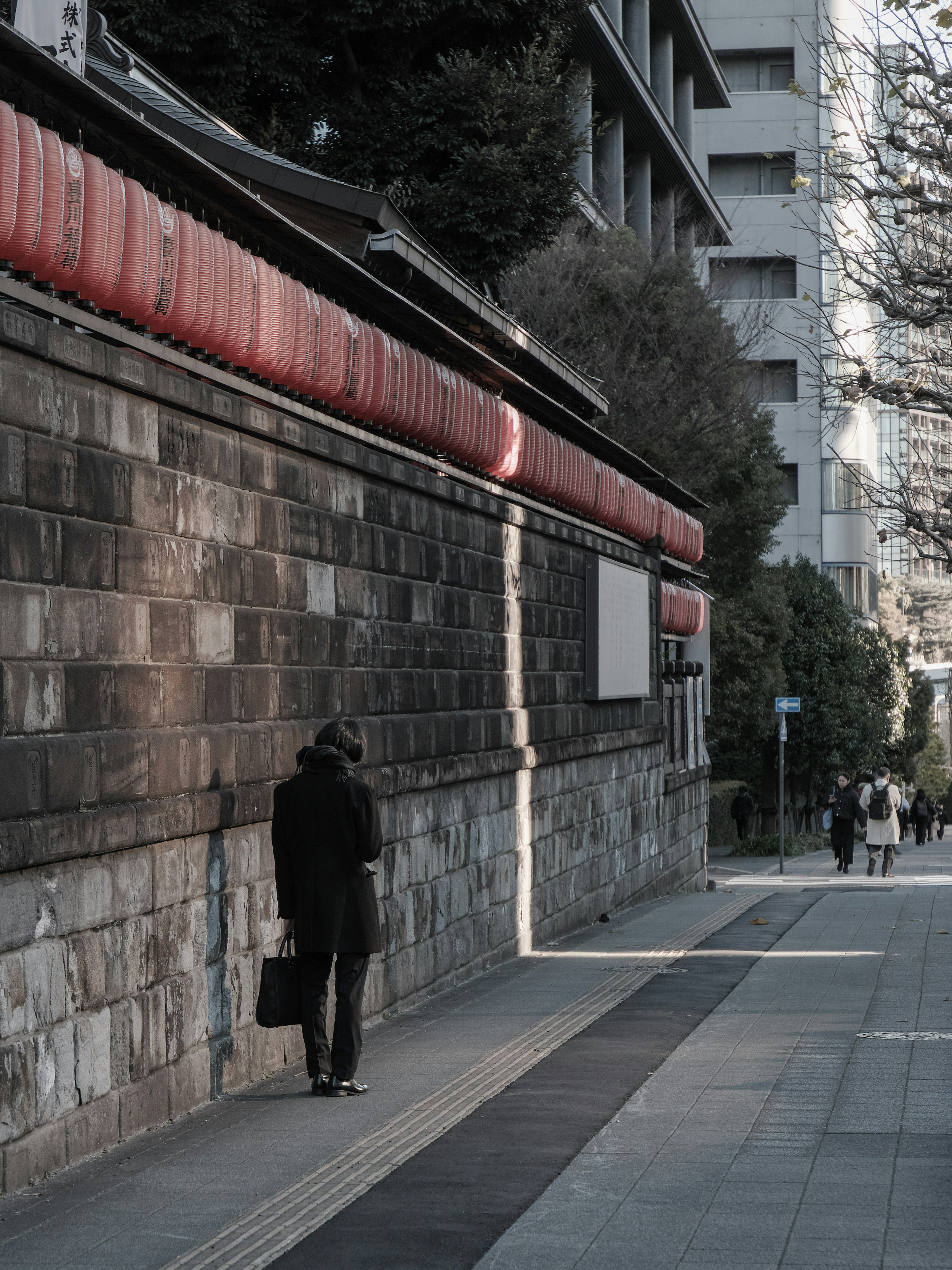 Geschäftsmann, der entlang einer Stadtstraße mit einer historischen Steinmauer geht