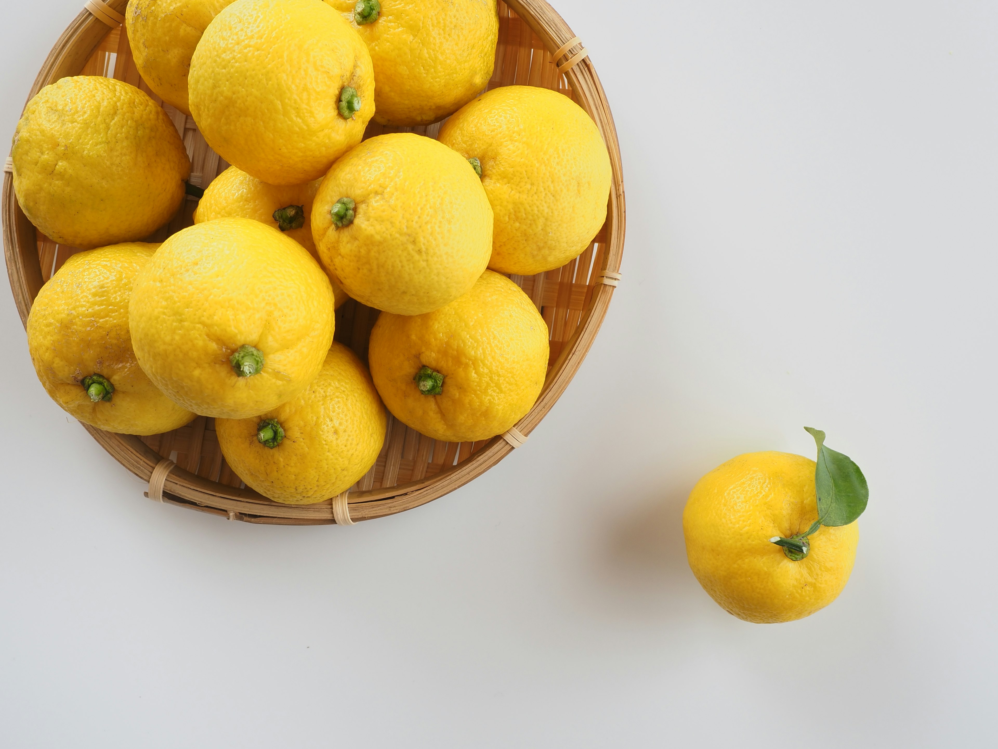 Un cesto di limoni gialli con un limone posato sul tavolo