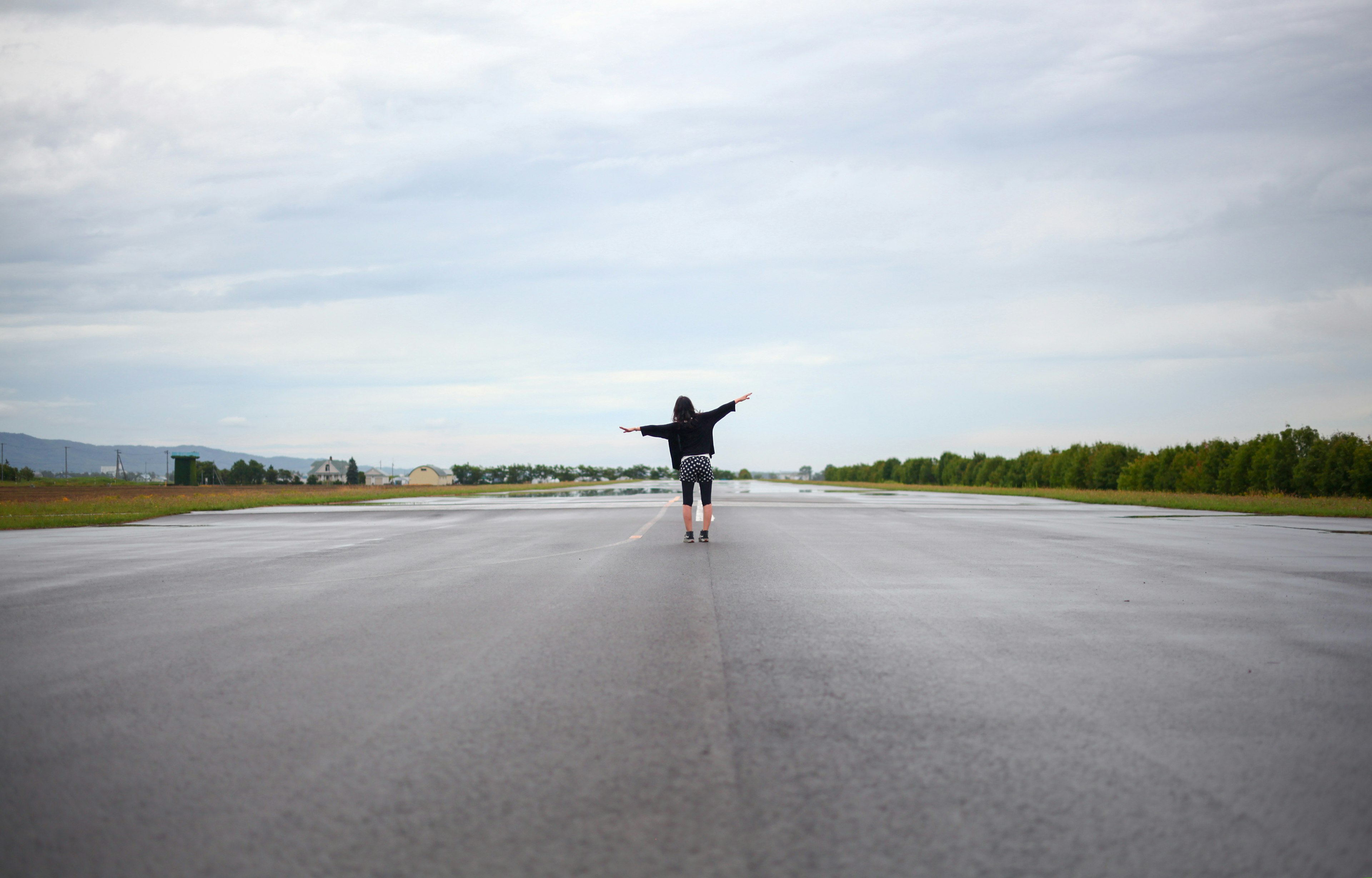 Foto di una persona che si trova nel mezzo di una pista con le braccia aperte