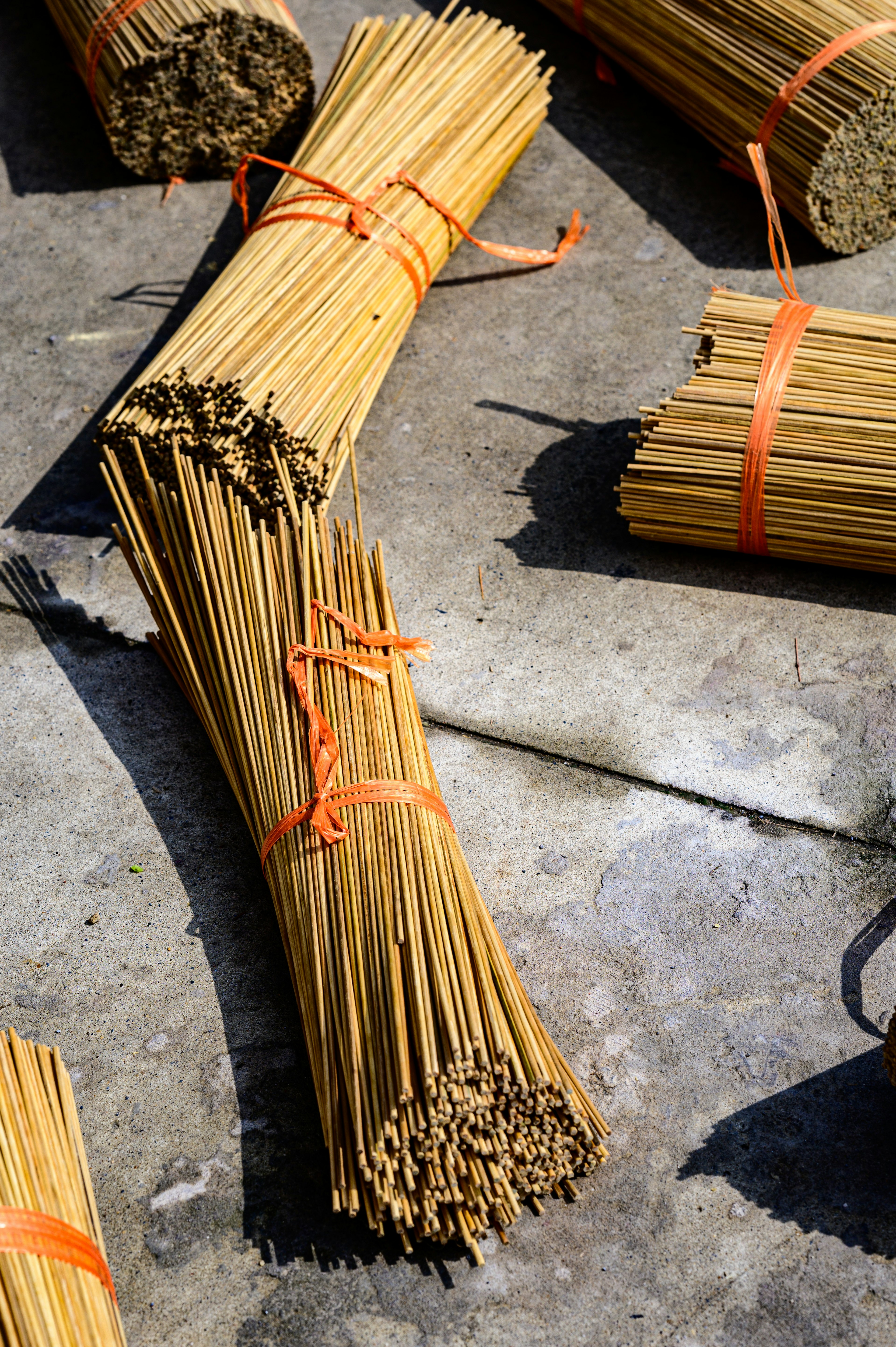 Bundles of straw sticks tied with orange strings on a concrete surface