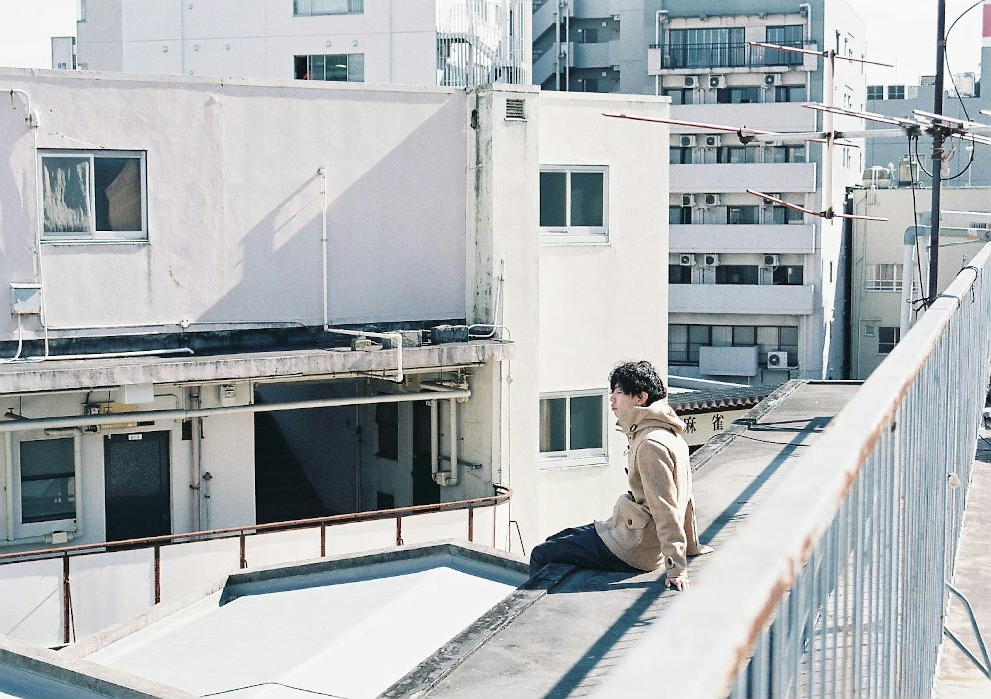 A man sitting on a rooftop overlooking a cityscape