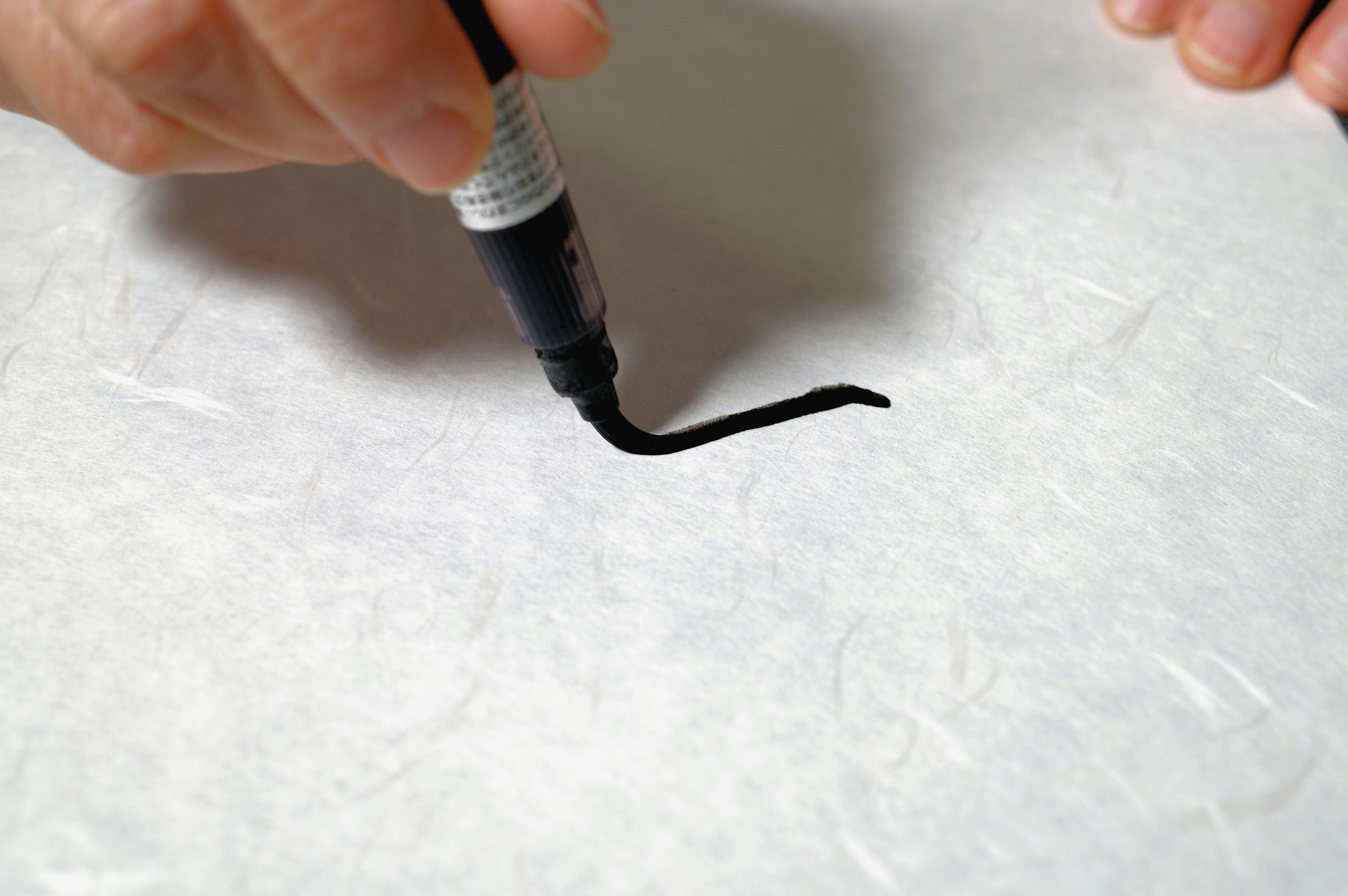 Eine Hand zieht mit einem Marker eine schwarze Linie auf weißem Papier