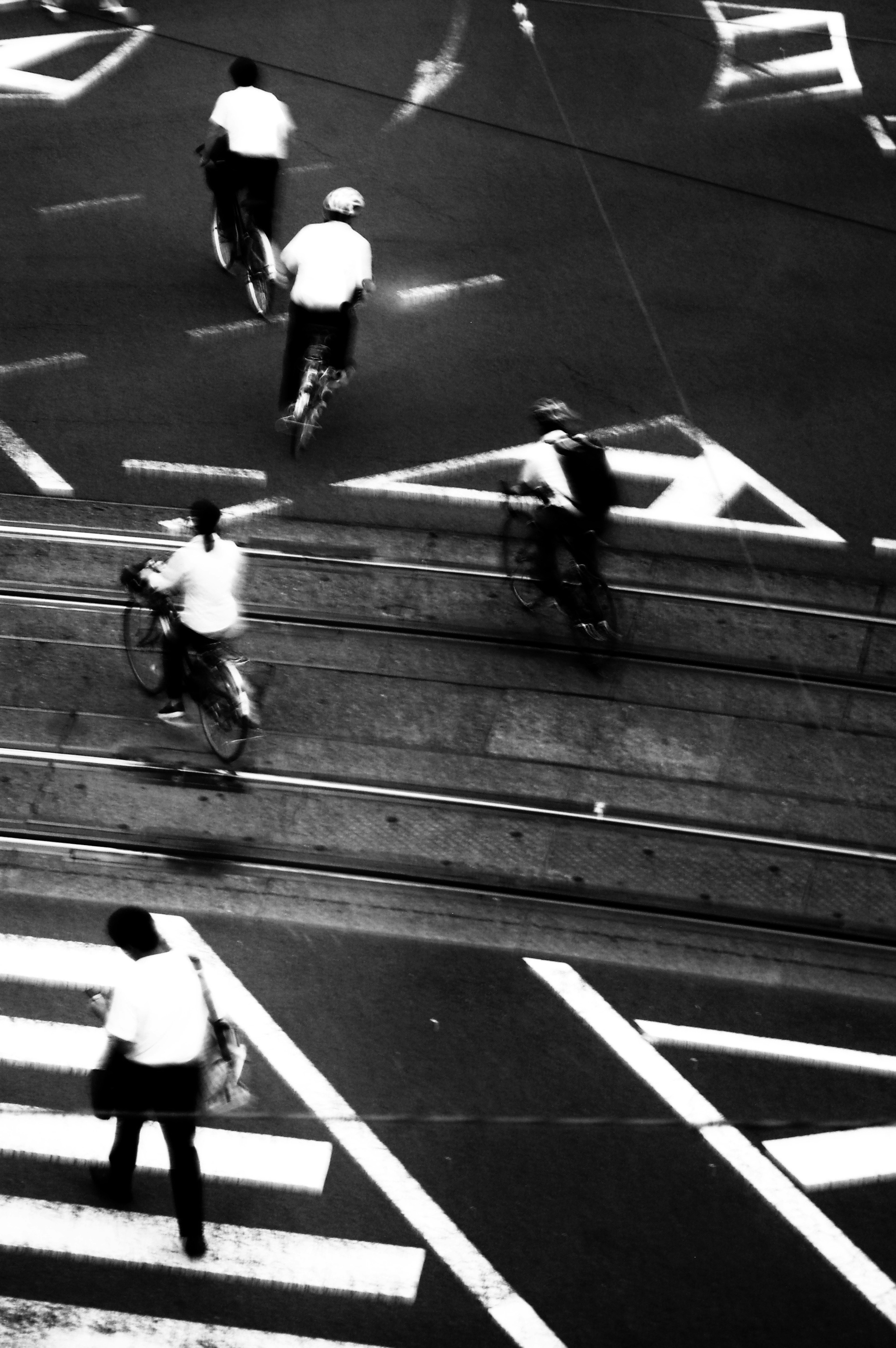 Scène de rue en noir et blanc avec des cyclistes traversant des intersections