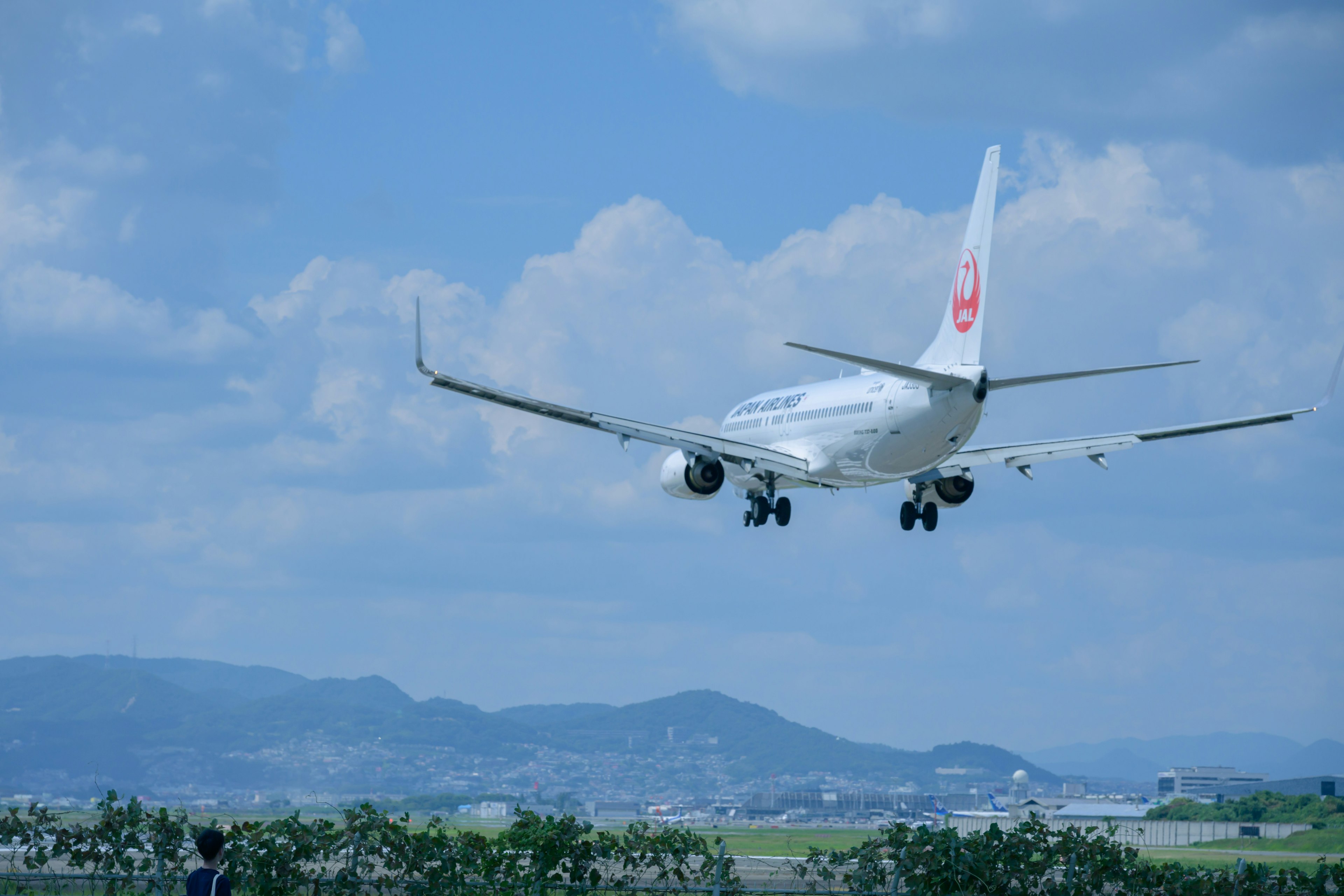 Airplane landing under a blue sky with mountains in the background