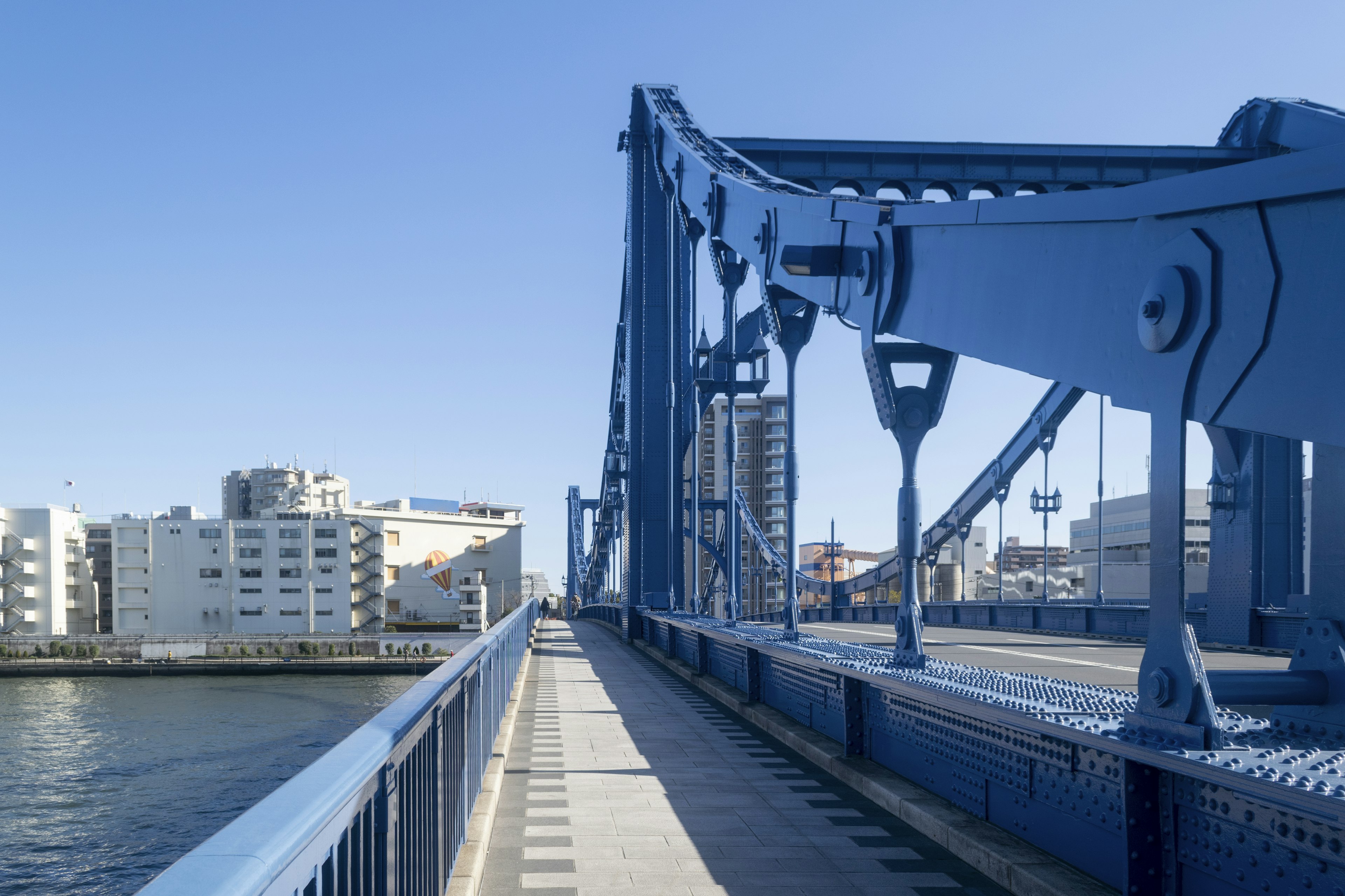 Blaue Brückenstruktur mit Stadtlandschaft im Hintergrund