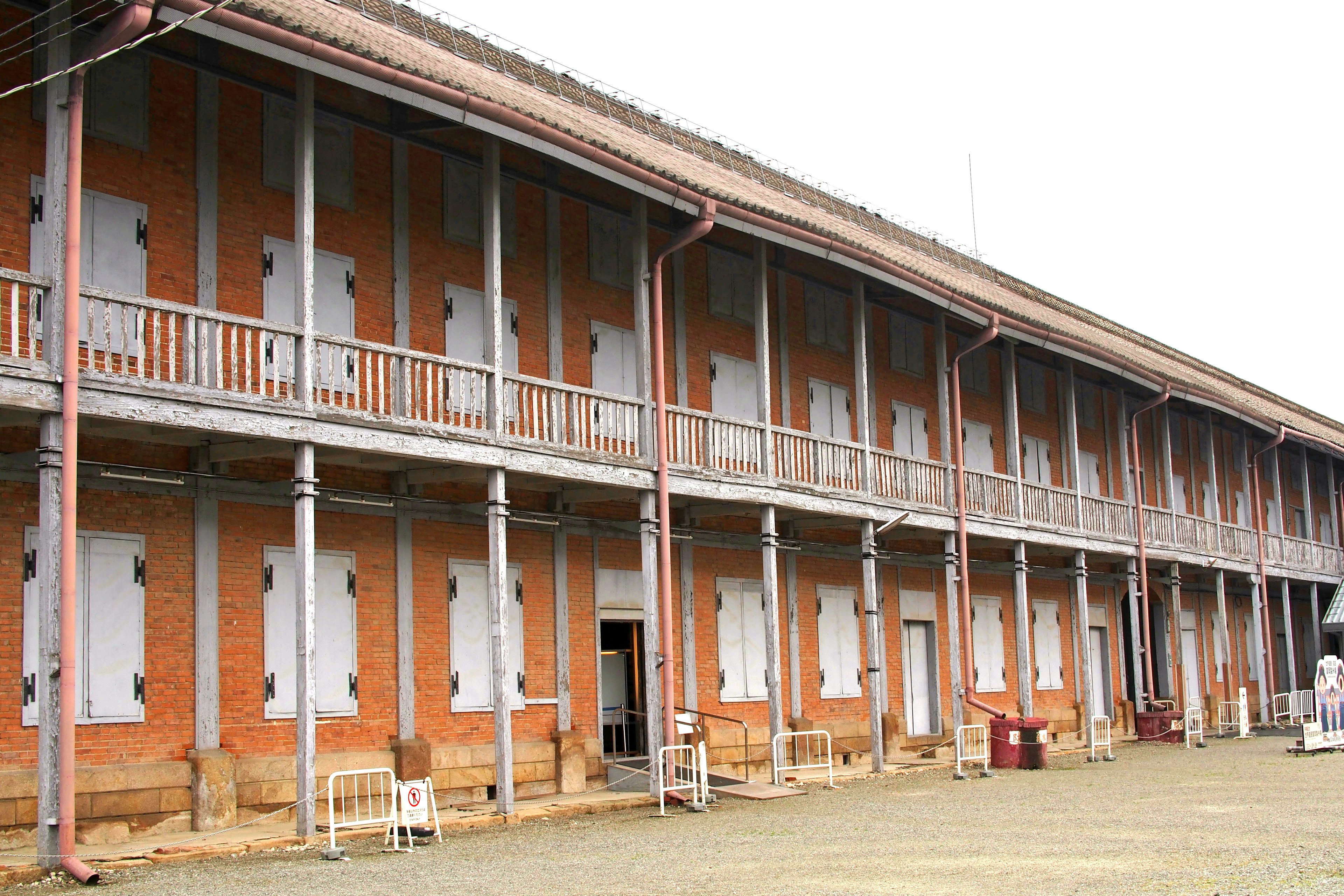 Long corridor of a brick building with balconies and boarded windows