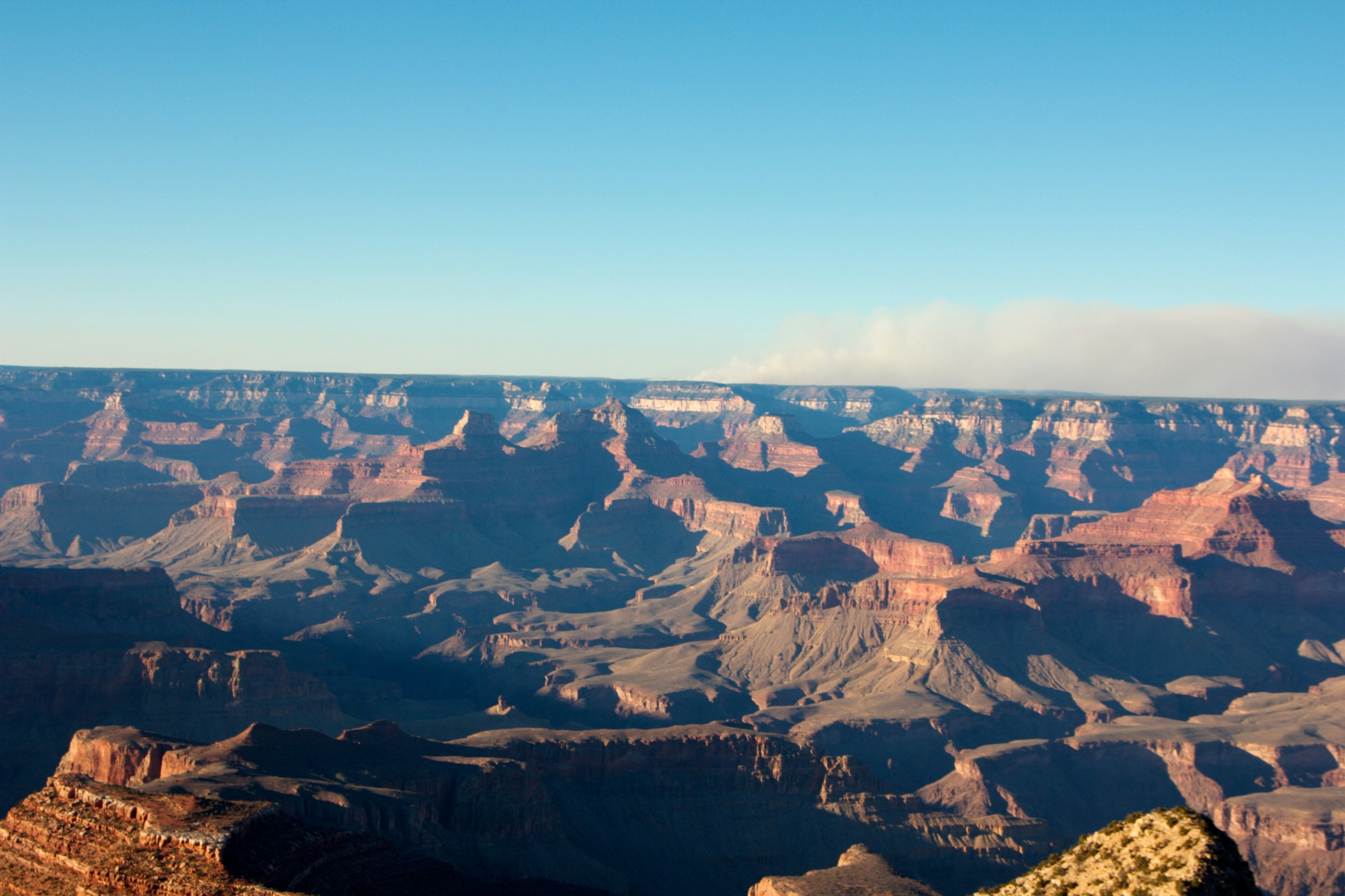 Vue expansive du Grand Canyon avec ciel bleu et formations rocheuses rouges en couches