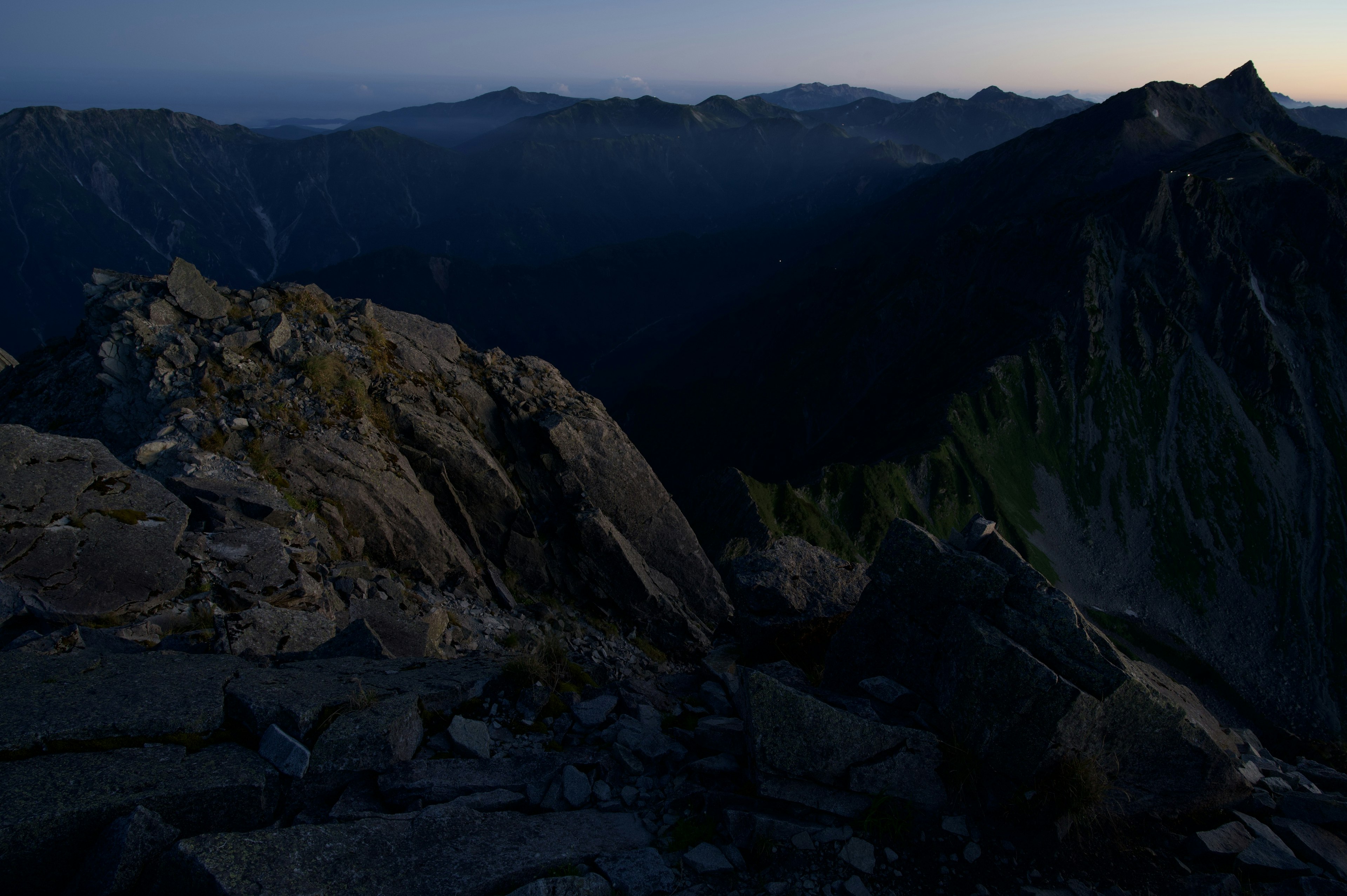 Vista del atardecer desde la cima de la montaña rocas en primer plano con montañas en silueta