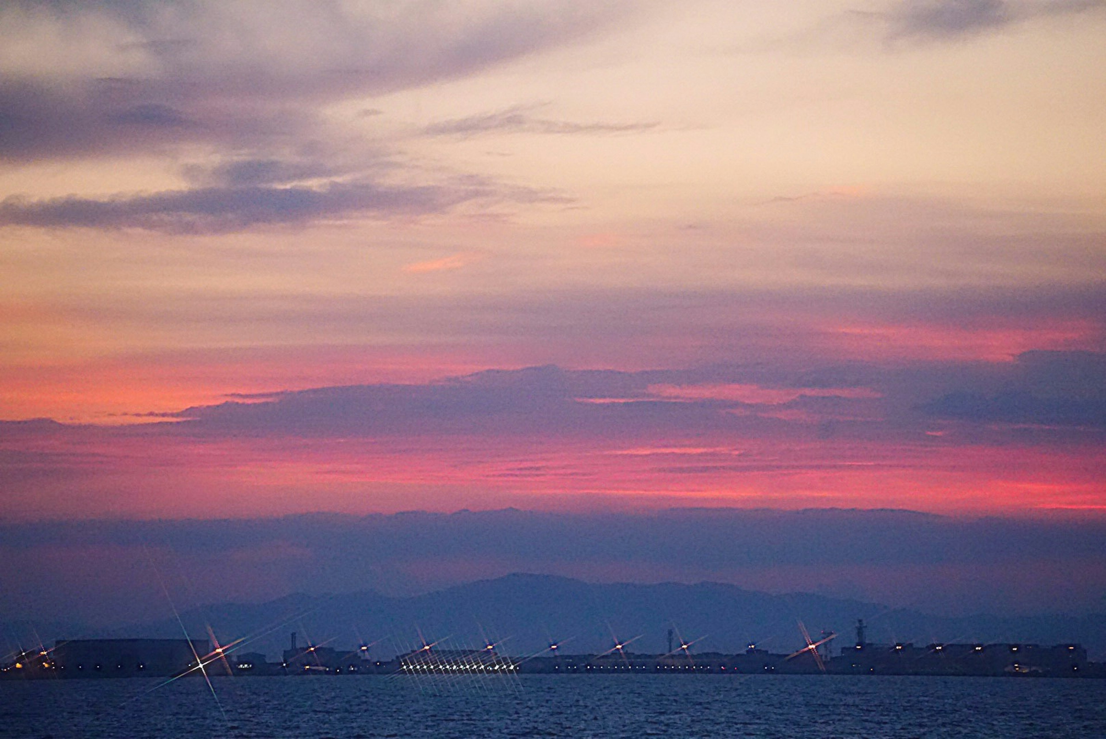 夕焼けの海と灯りを伴った港の風景