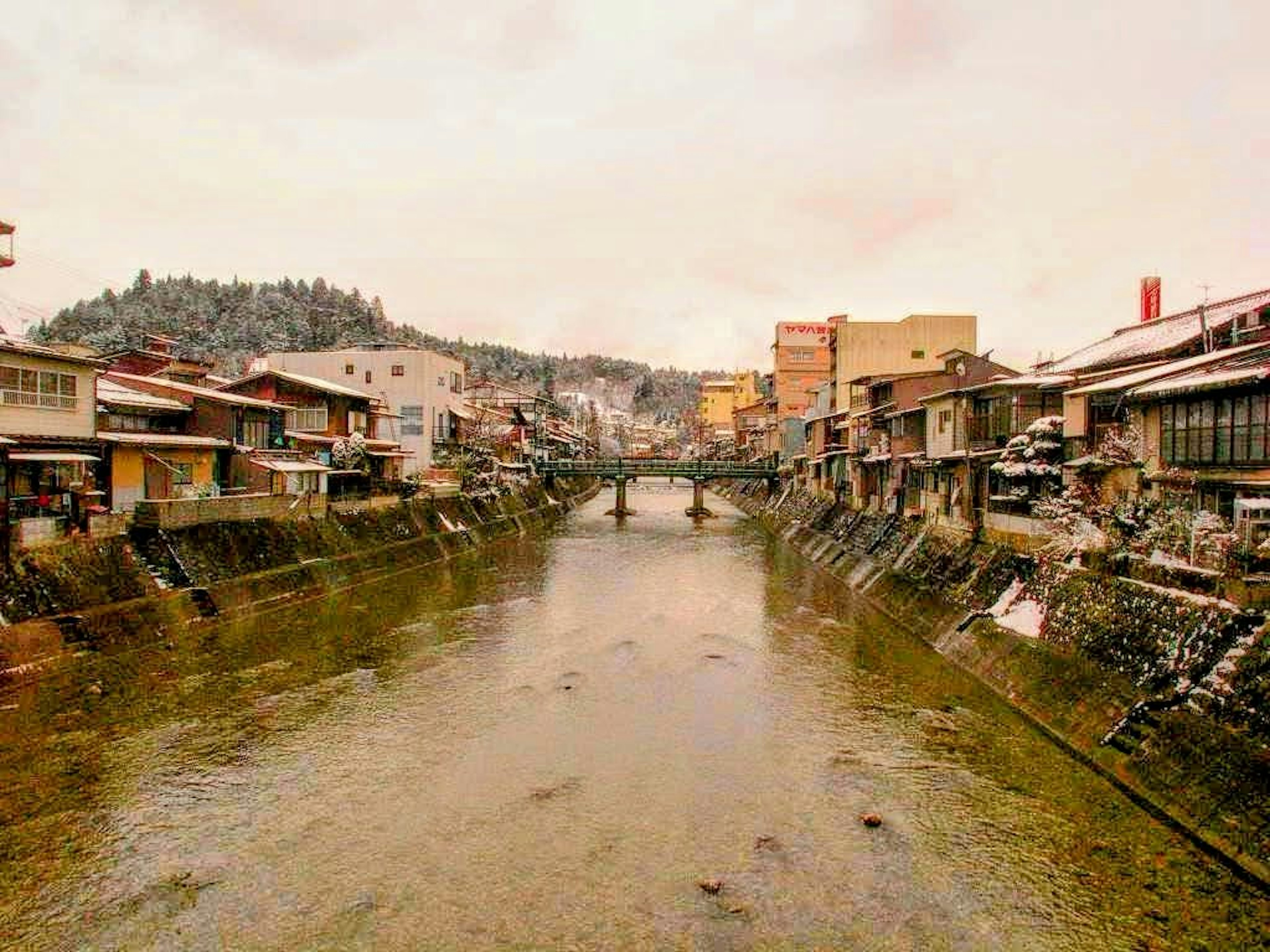 Scenic view of a snowy riverside town with a bridge