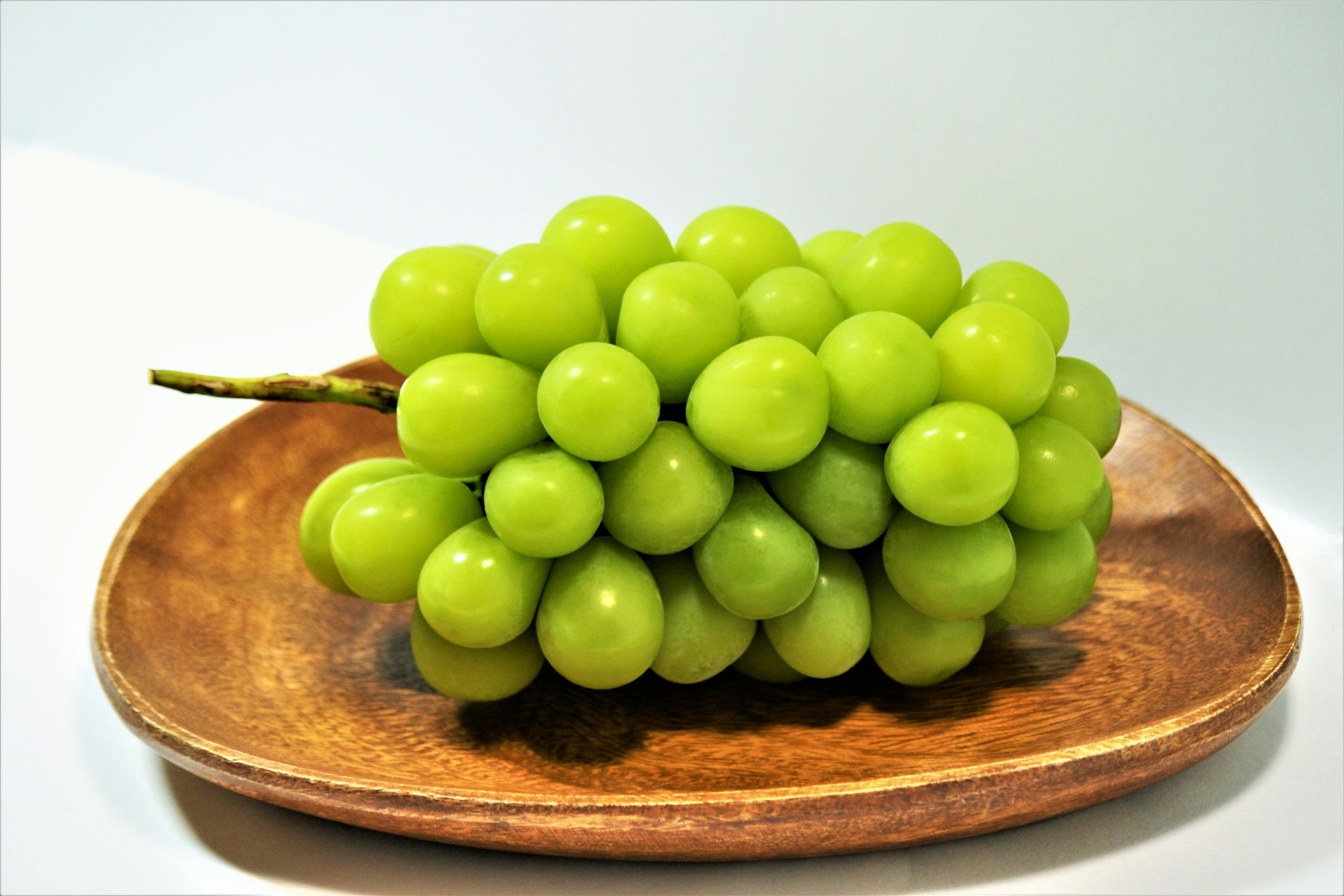 Une grappe de raisins verts sur une assiette en bois