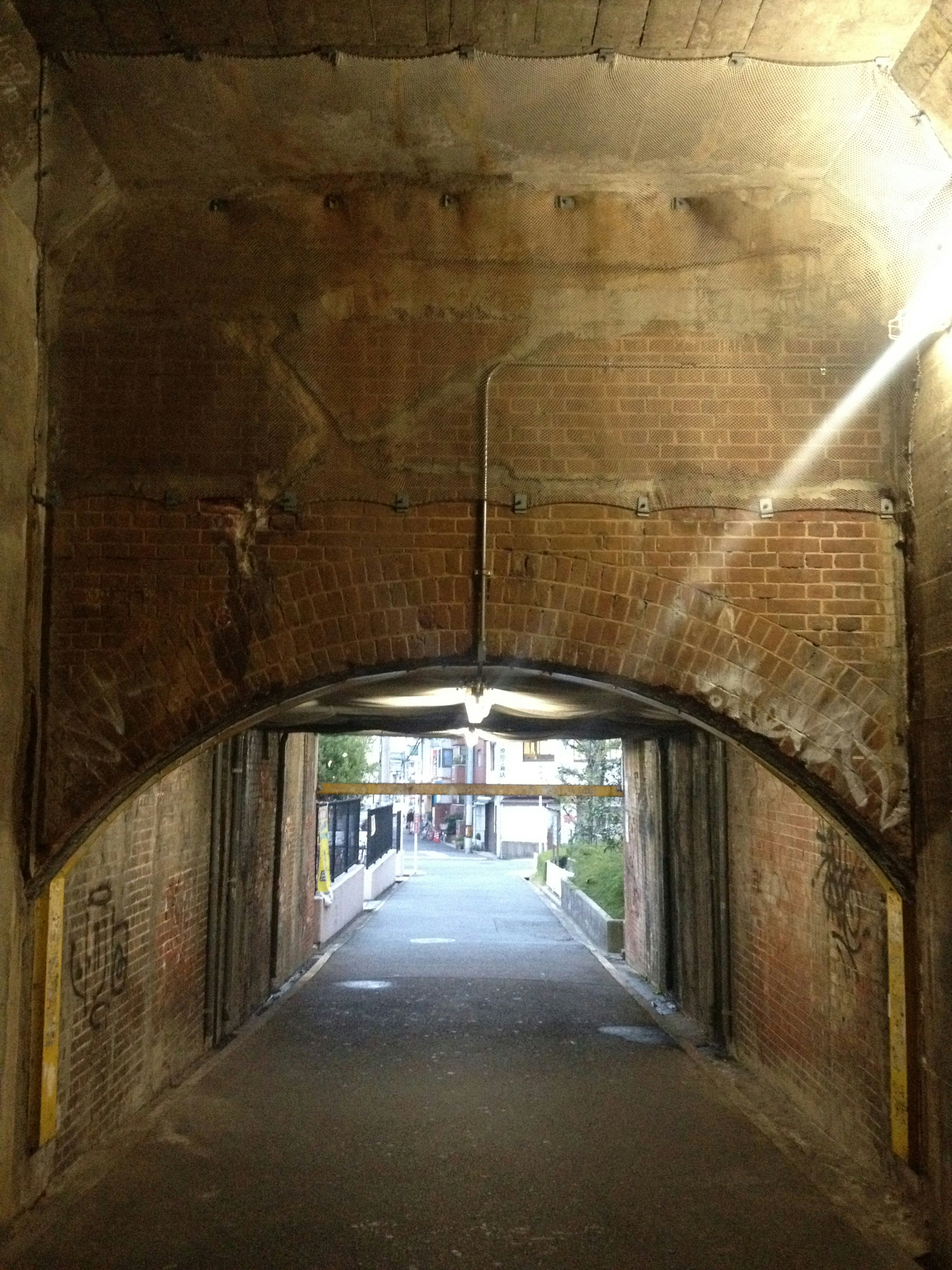 Vue à travers un ancien tunnel en briques en arc montrant un chemin au-delà