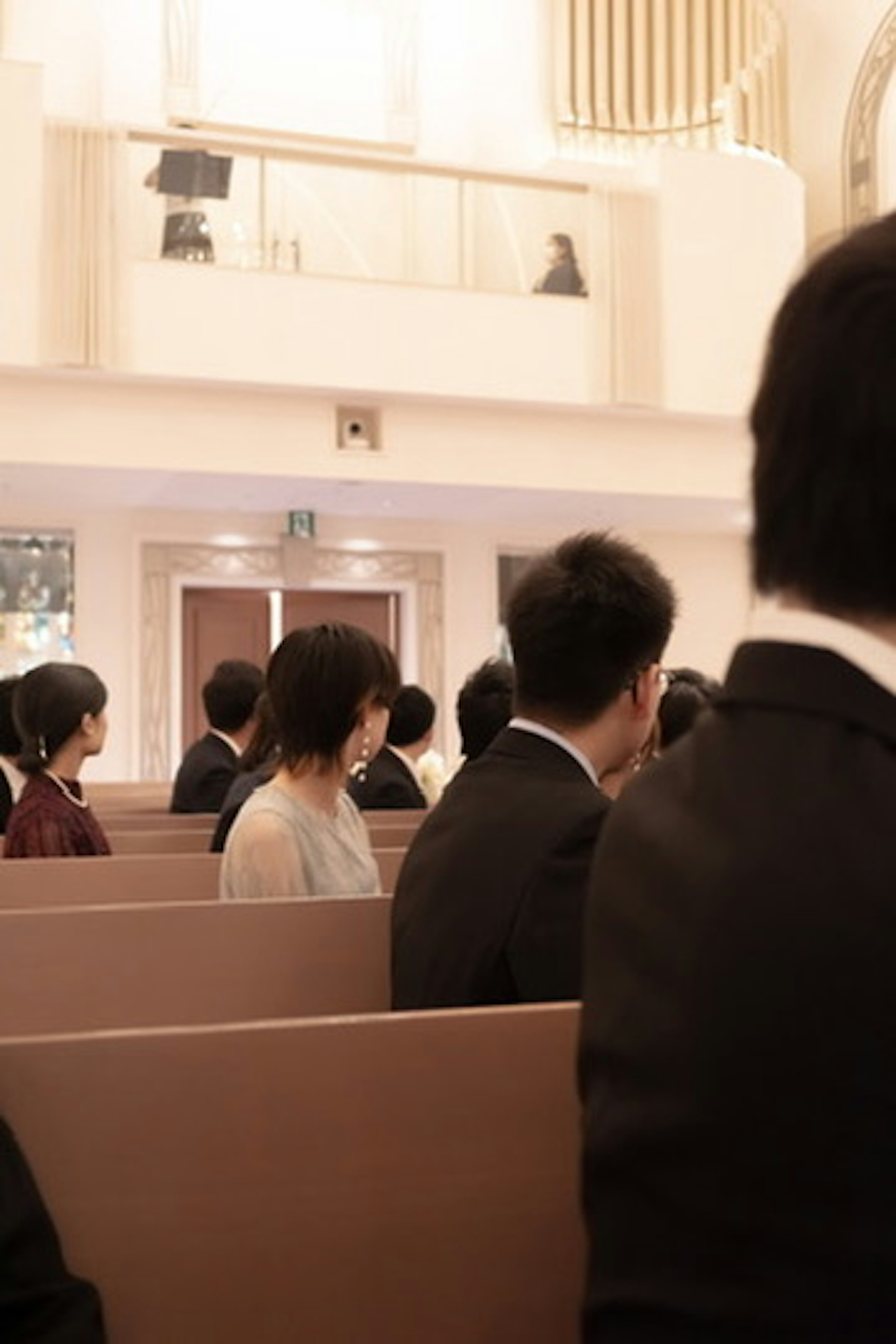 Menschen, die in einer Kirche sitzen, mit sanften Farben und schwarzen Anzügen