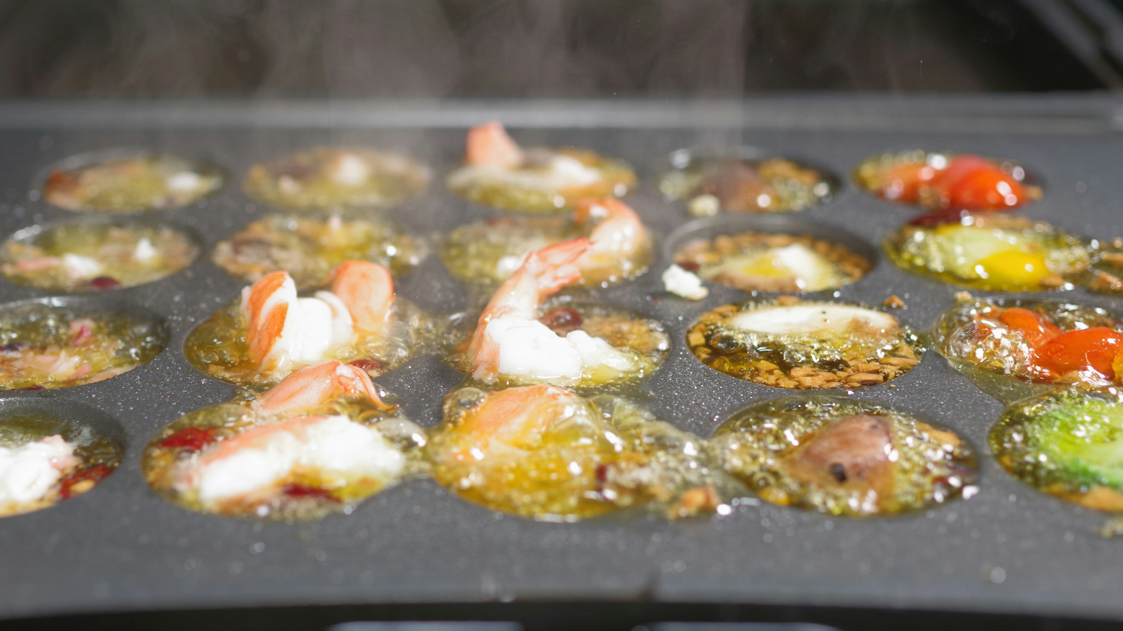 Cooking takoyaki on a hot grill with steam rising