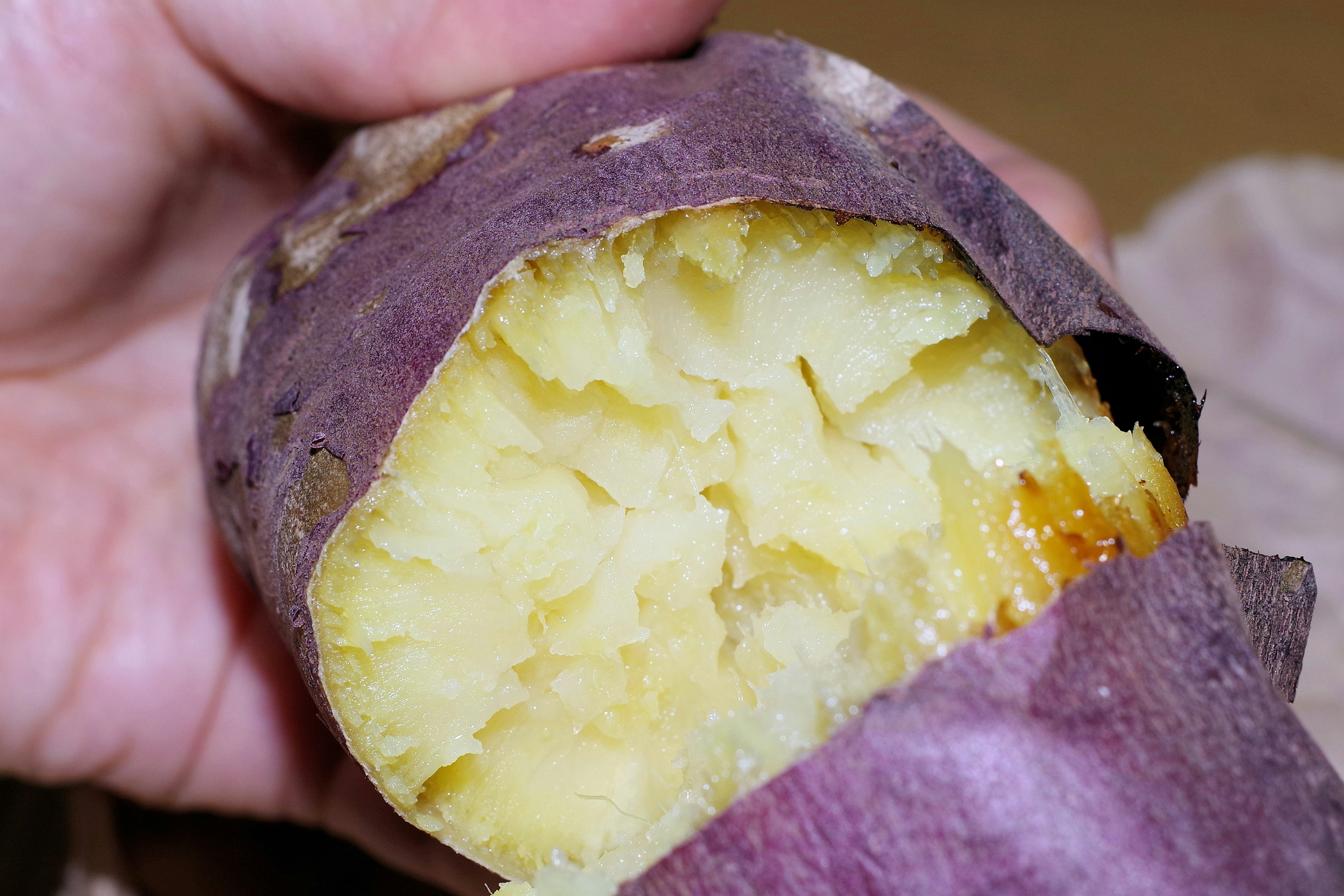 Una sección de una batata morada sostenida en una mano