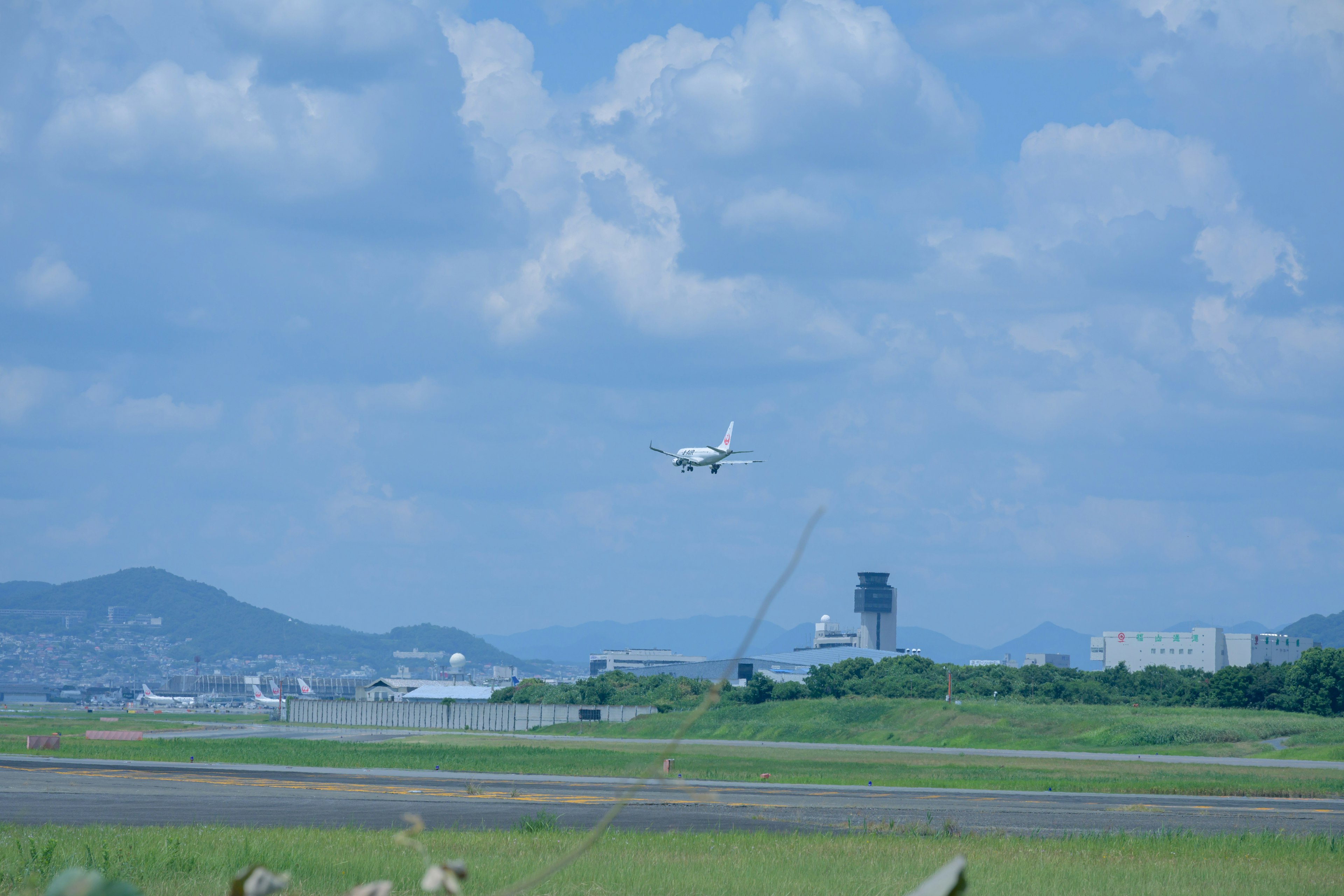 青空の下で飛行機が着陸する様子と周囲の風景