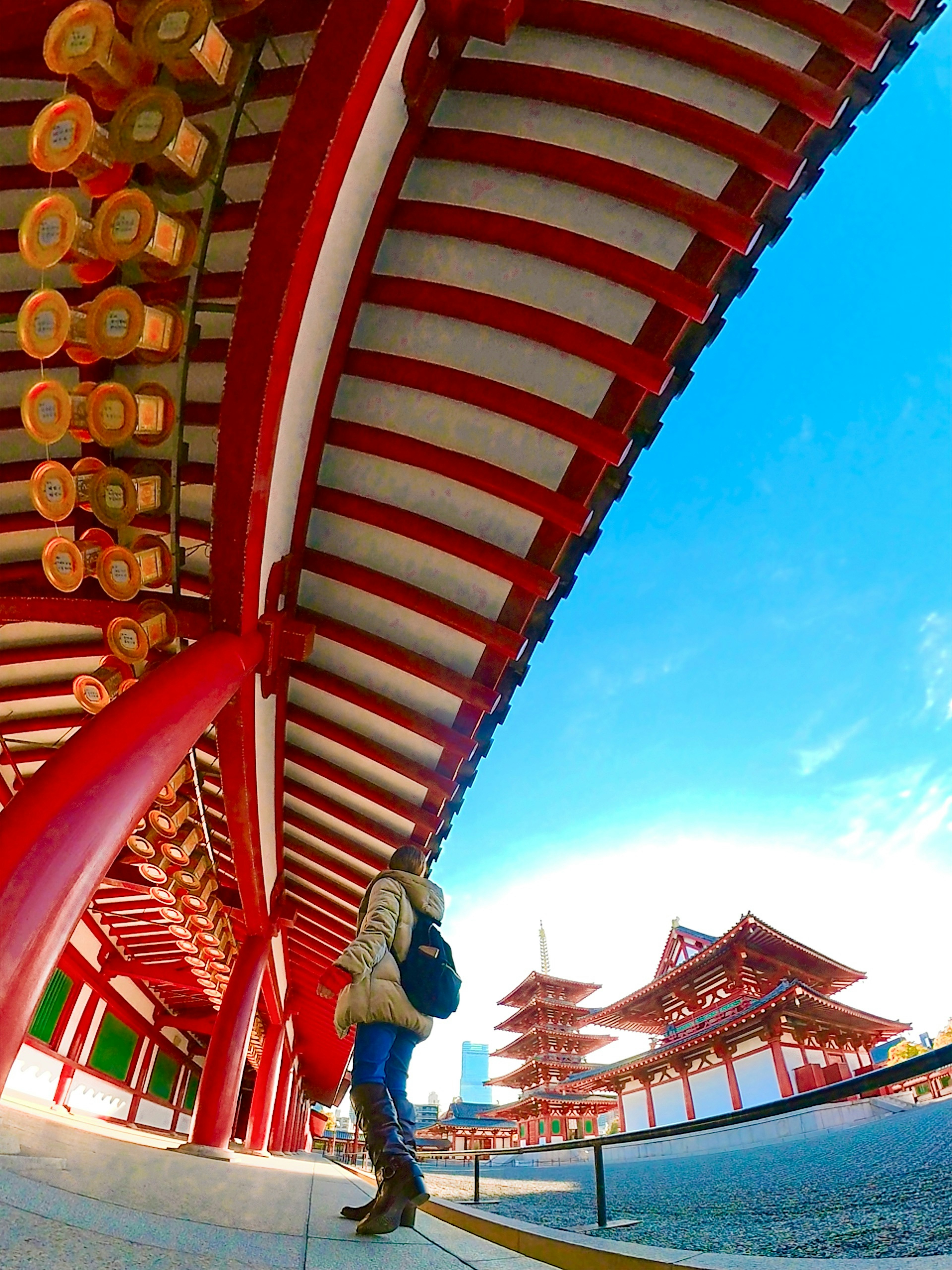 Person standing in front of traditional red-roofed buildings under a blue sky