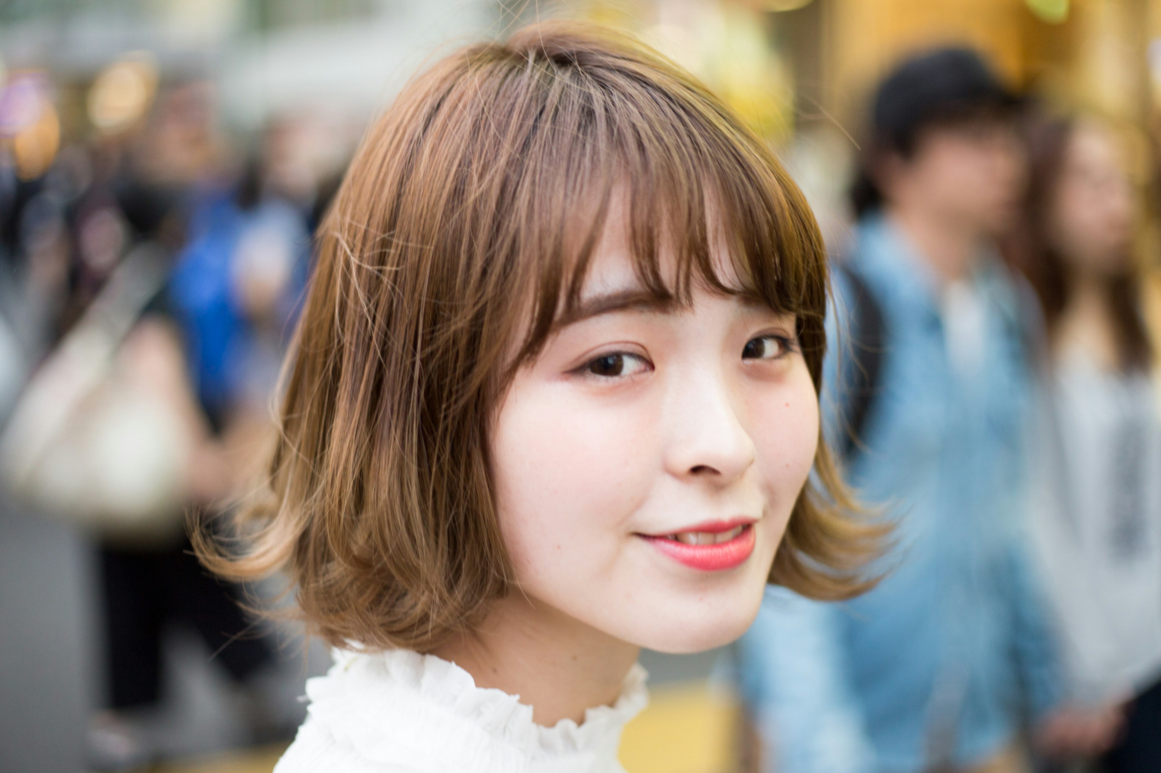 Femme souriante avec des cheveux courts dans une rue animée avec des gens