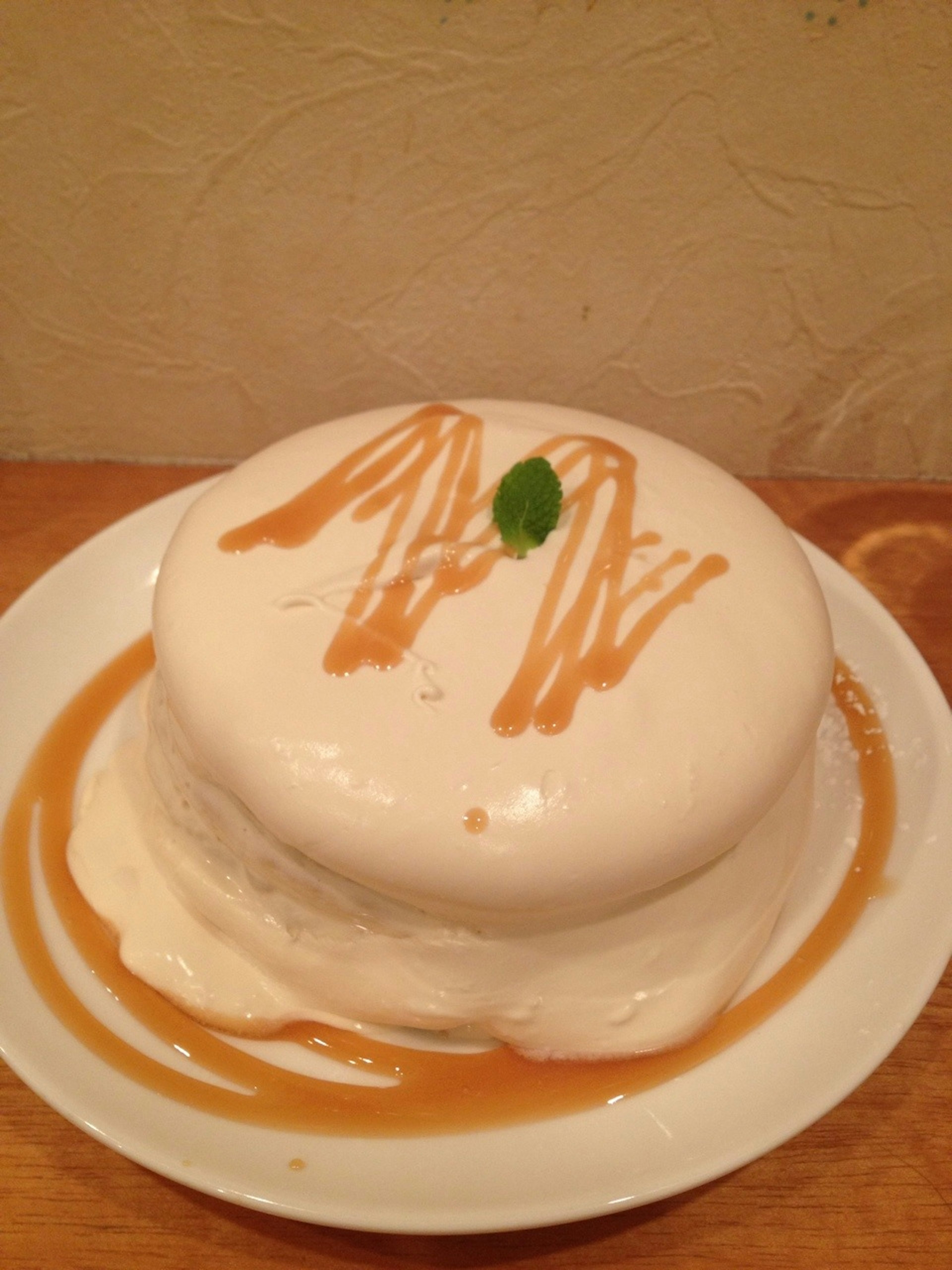 Creamy white cake topped with caramel sauce and a mint leaf