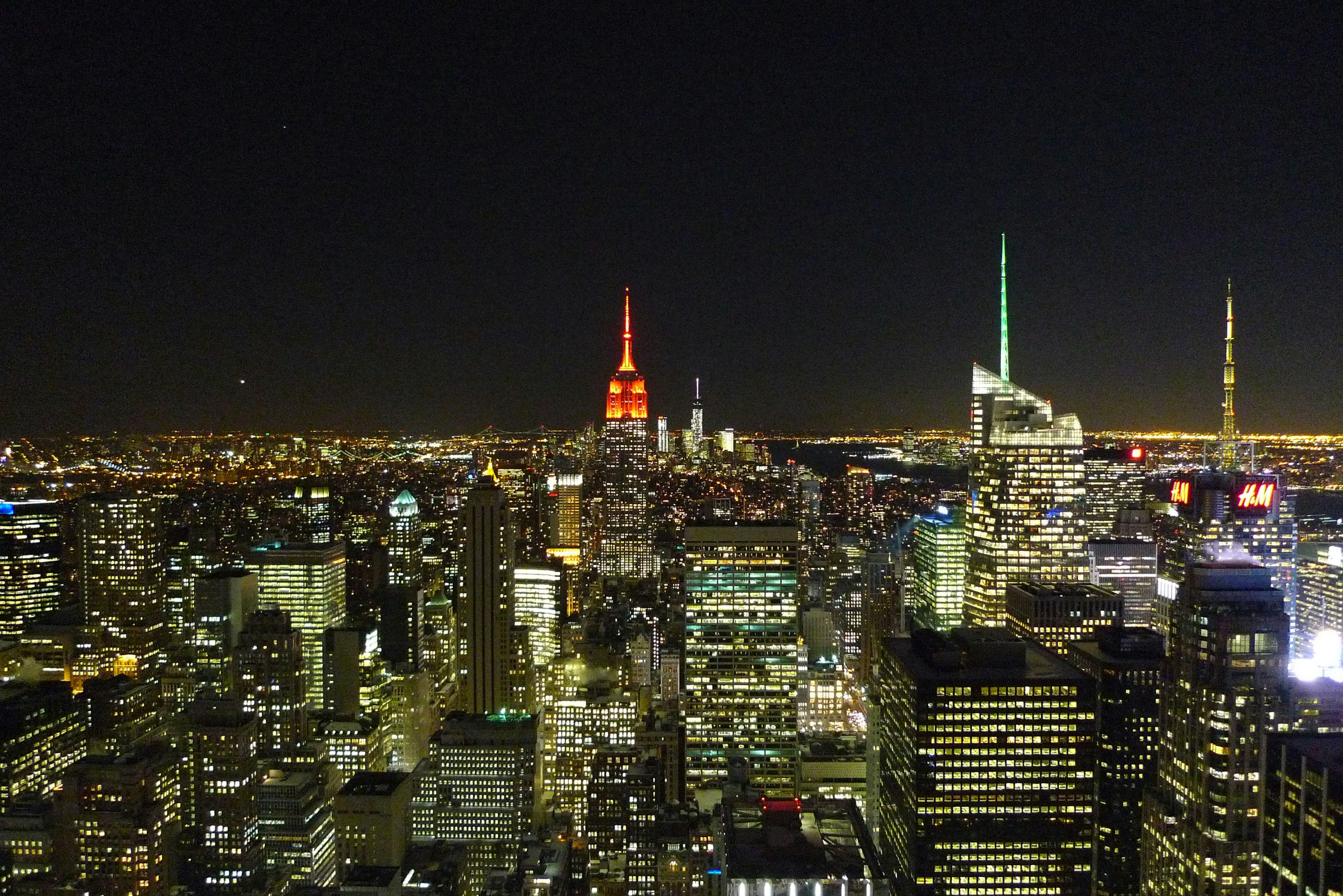 Panoramablick auf New York bei Nacht mit der orangefarbenen Spitze des Empire State Buildings