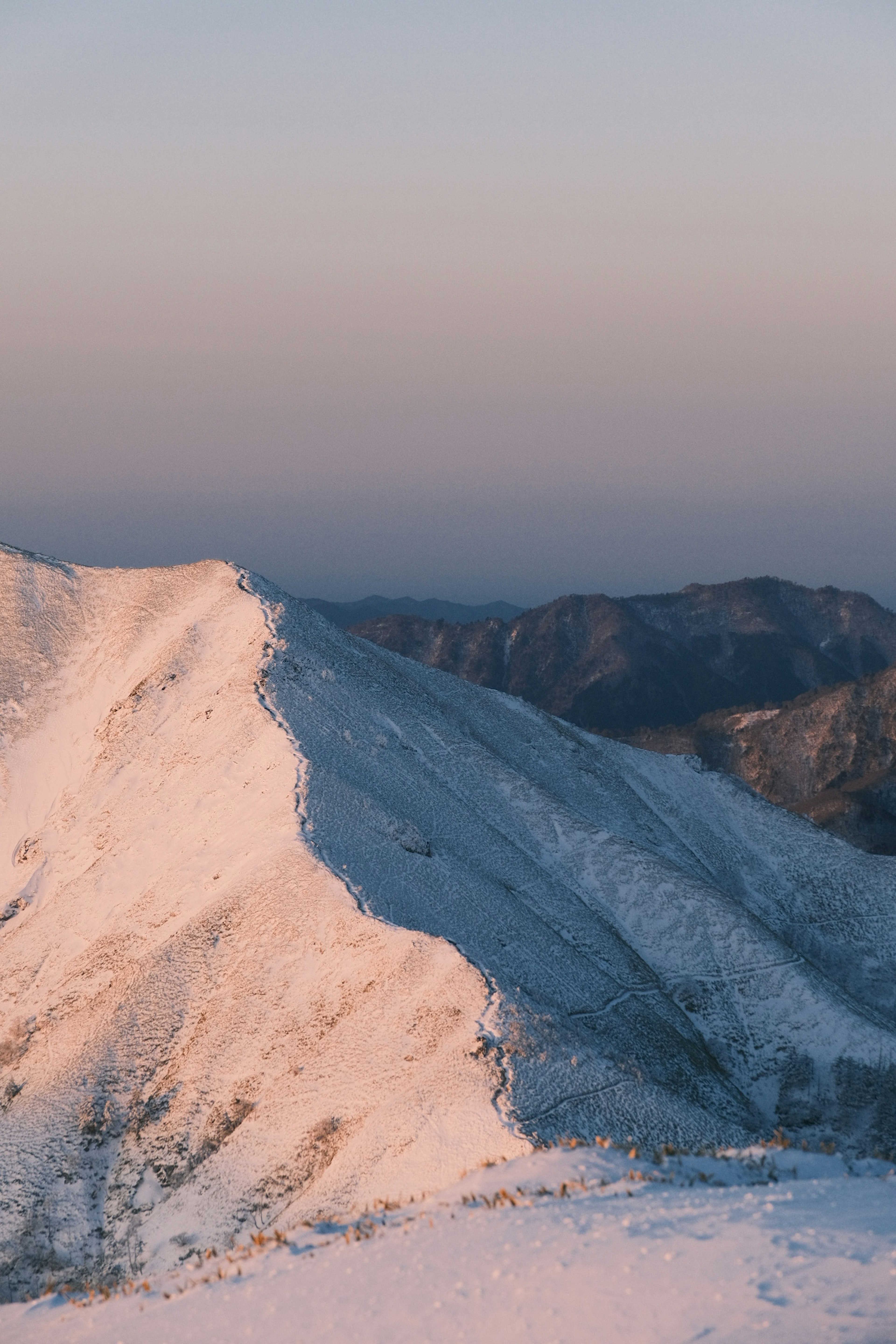 被雪覆蓋的山坡與寧靜的黃昏天空