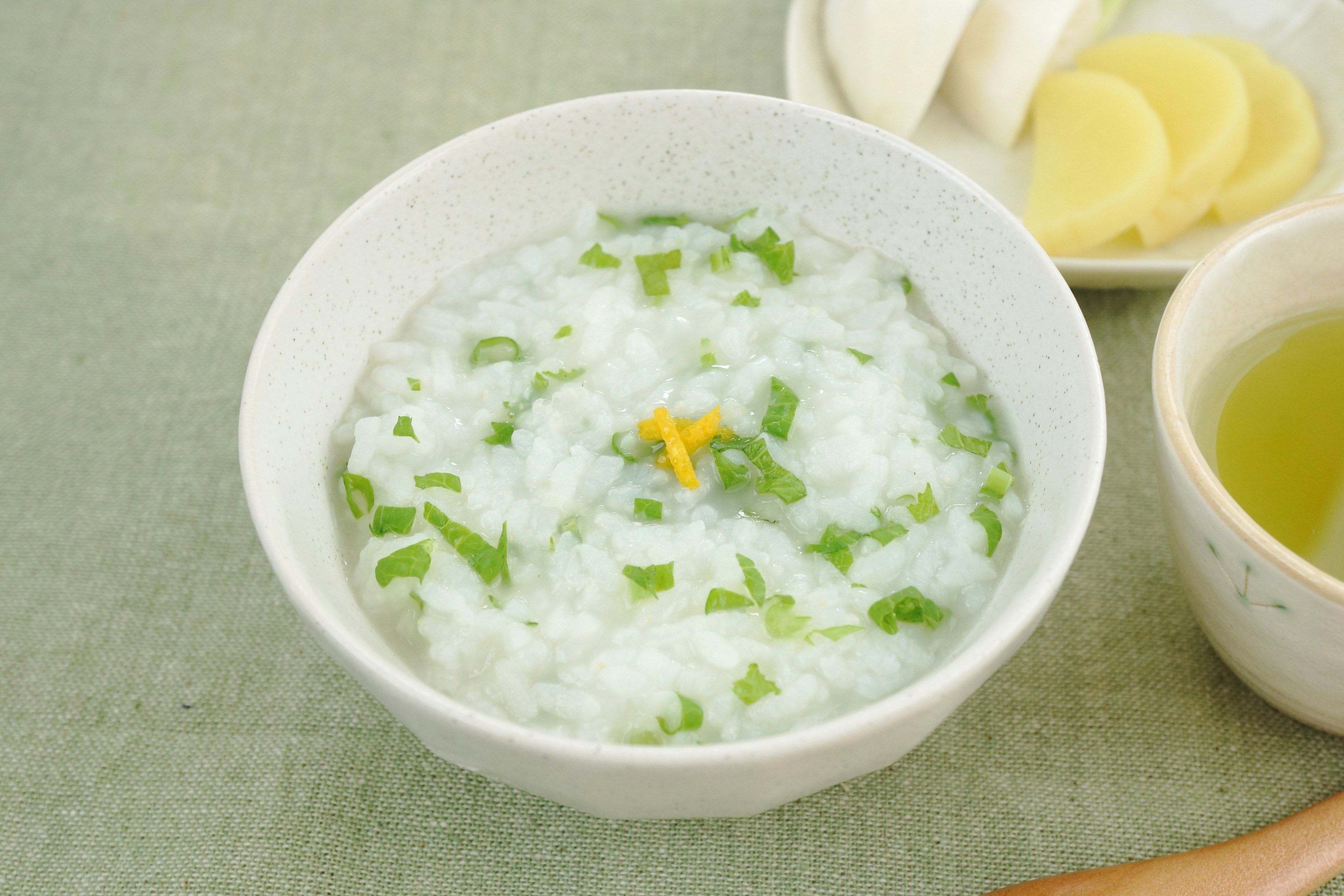 Tazón de gachas de arroz decorado con hierbas verdes y jengibre en rodajas