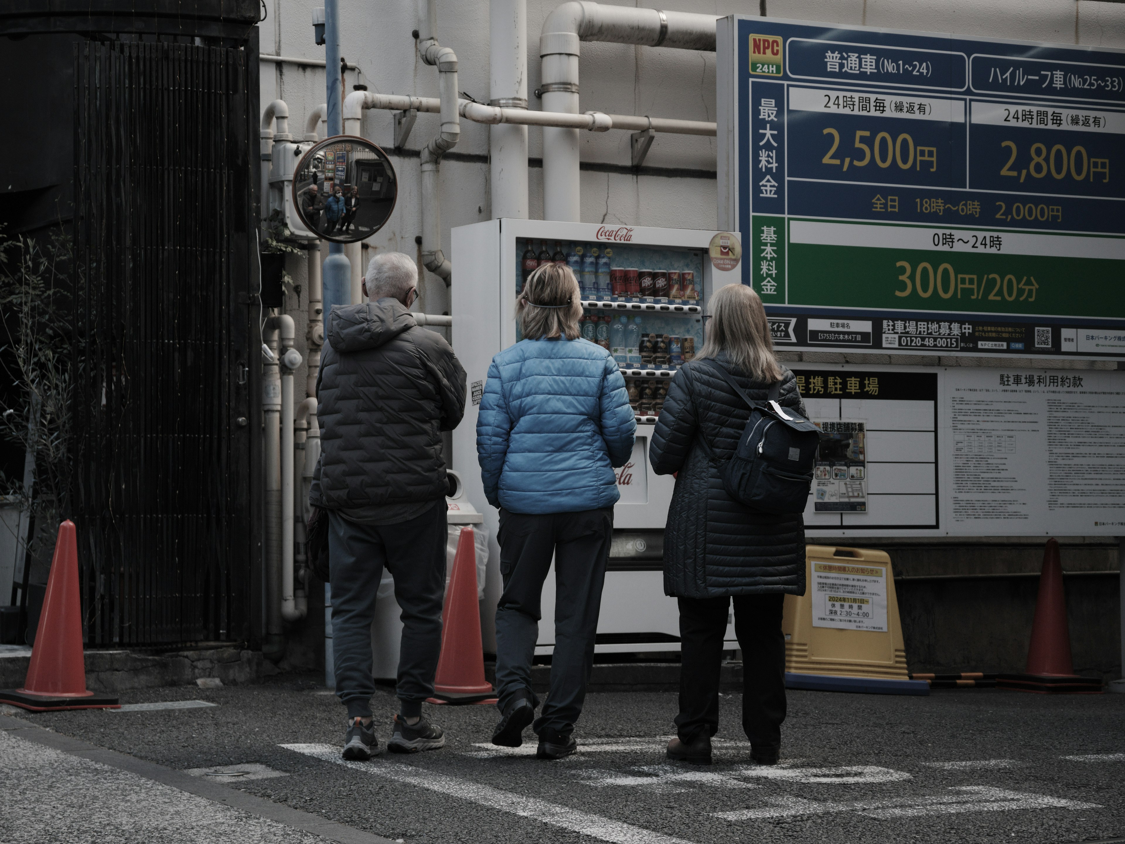 Three tourists standing at a street corner wearing jackets