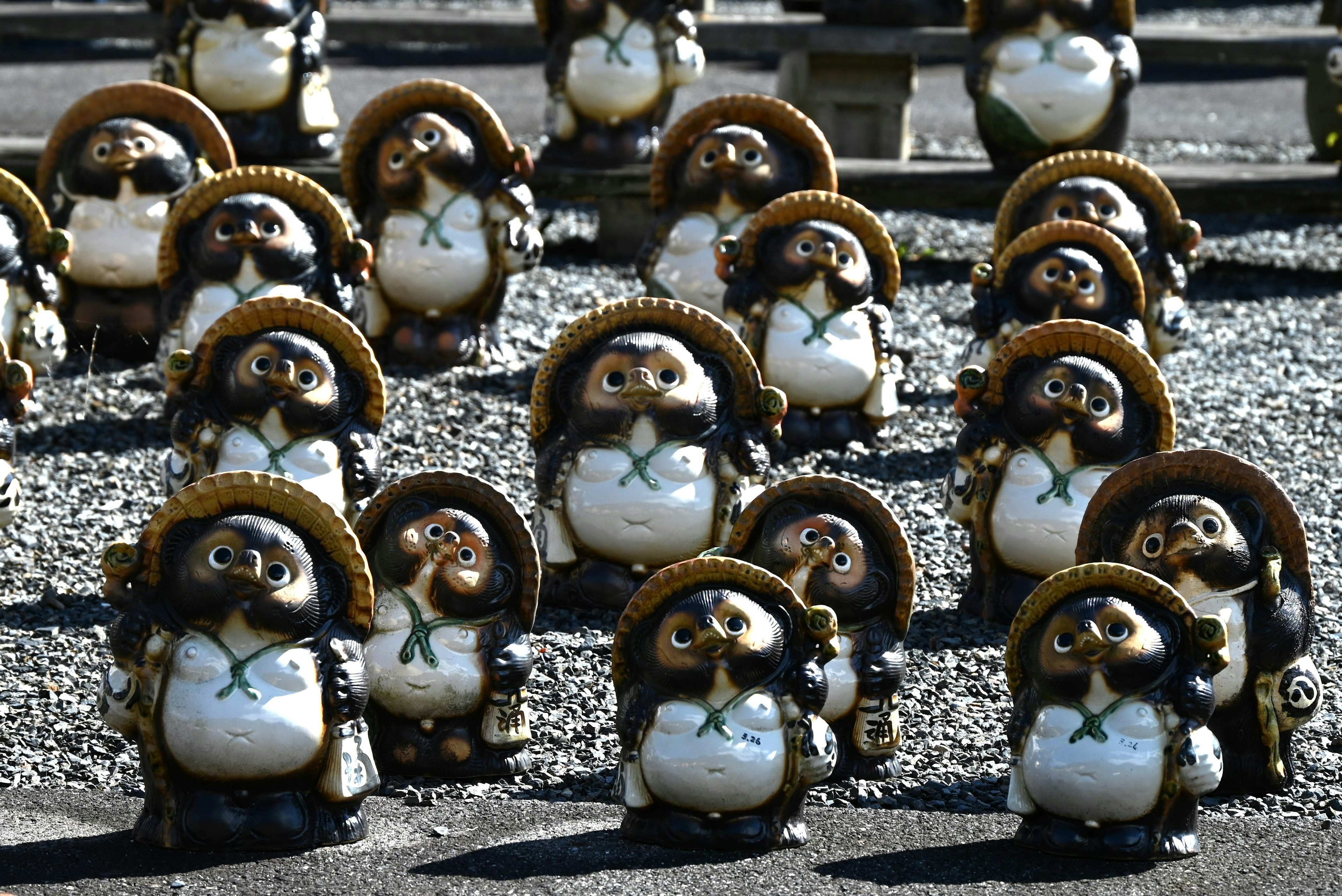 A collection of ceramic tanuki figurines arranged in a garden setting