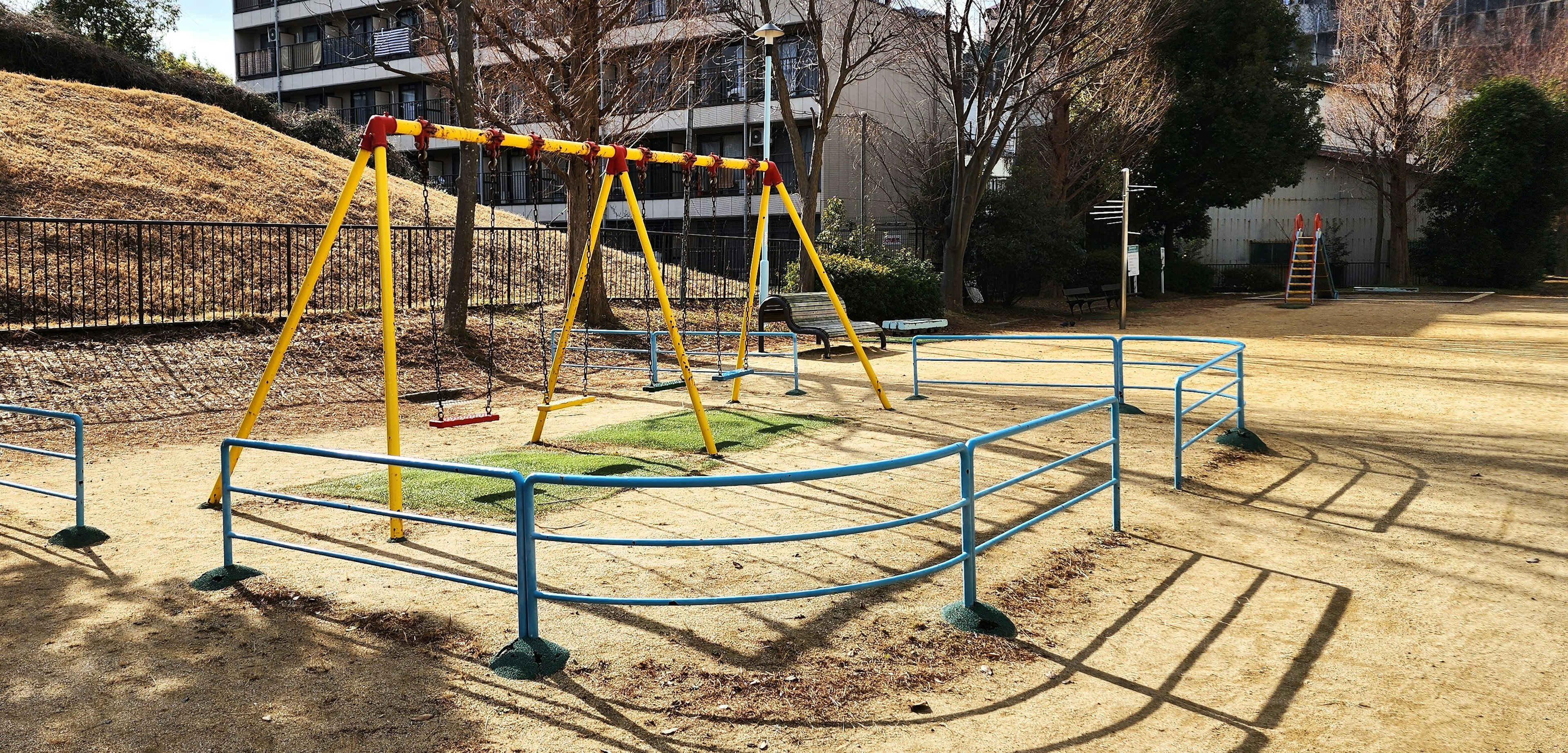 Spielplatz mit Schaukeln und umgebendem Zaun