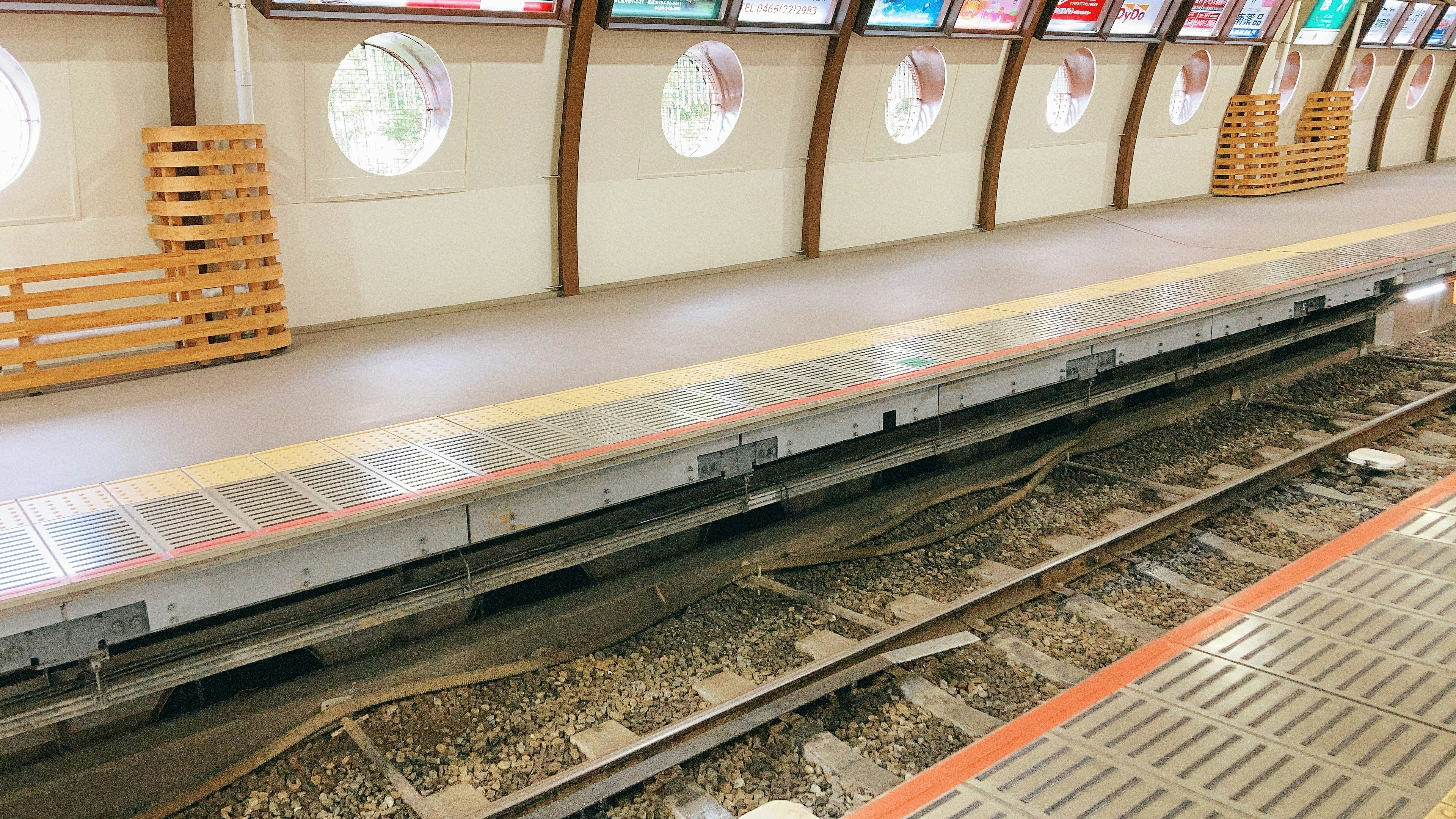 Immagine di una piattaforma di stazione ferroviaria con binari visibili e finestre rotonde