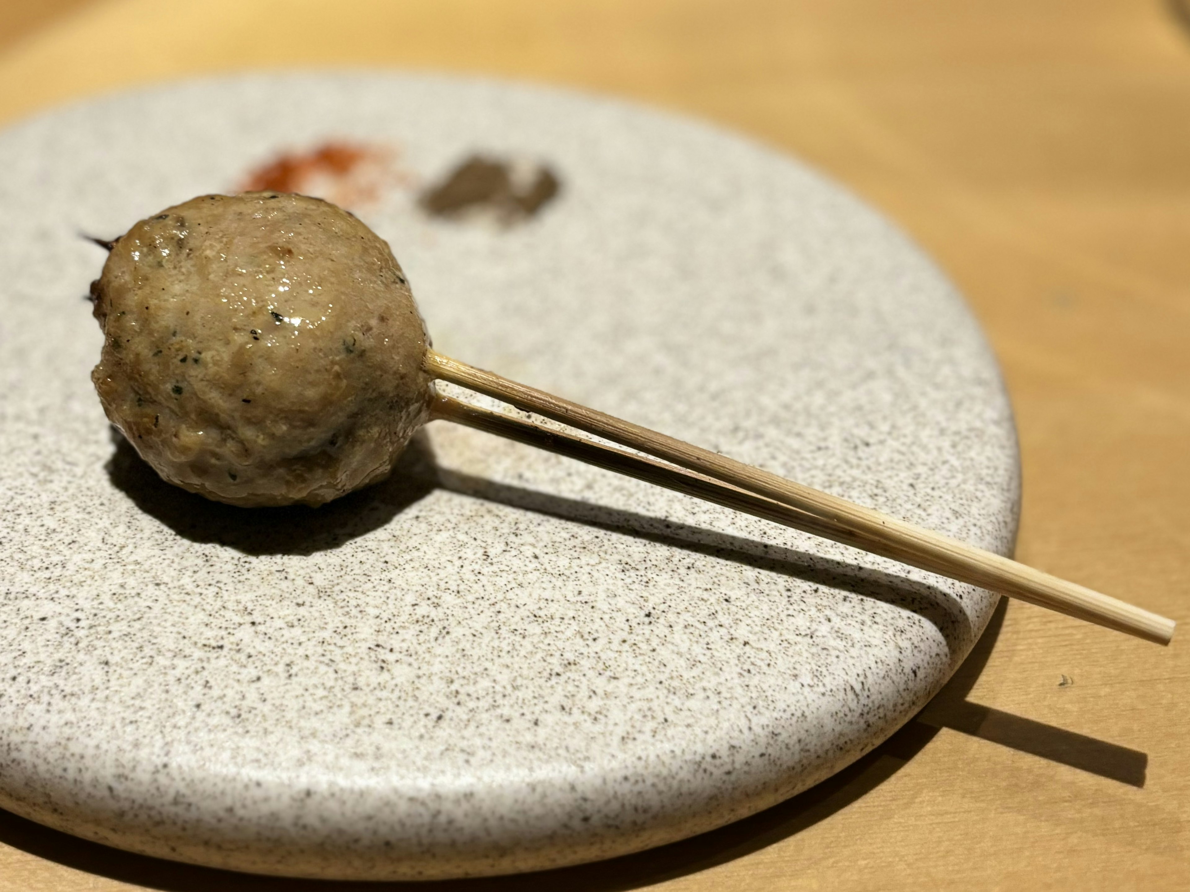 Une boulette de viande sur un bâton reposant sur une assiette ronde