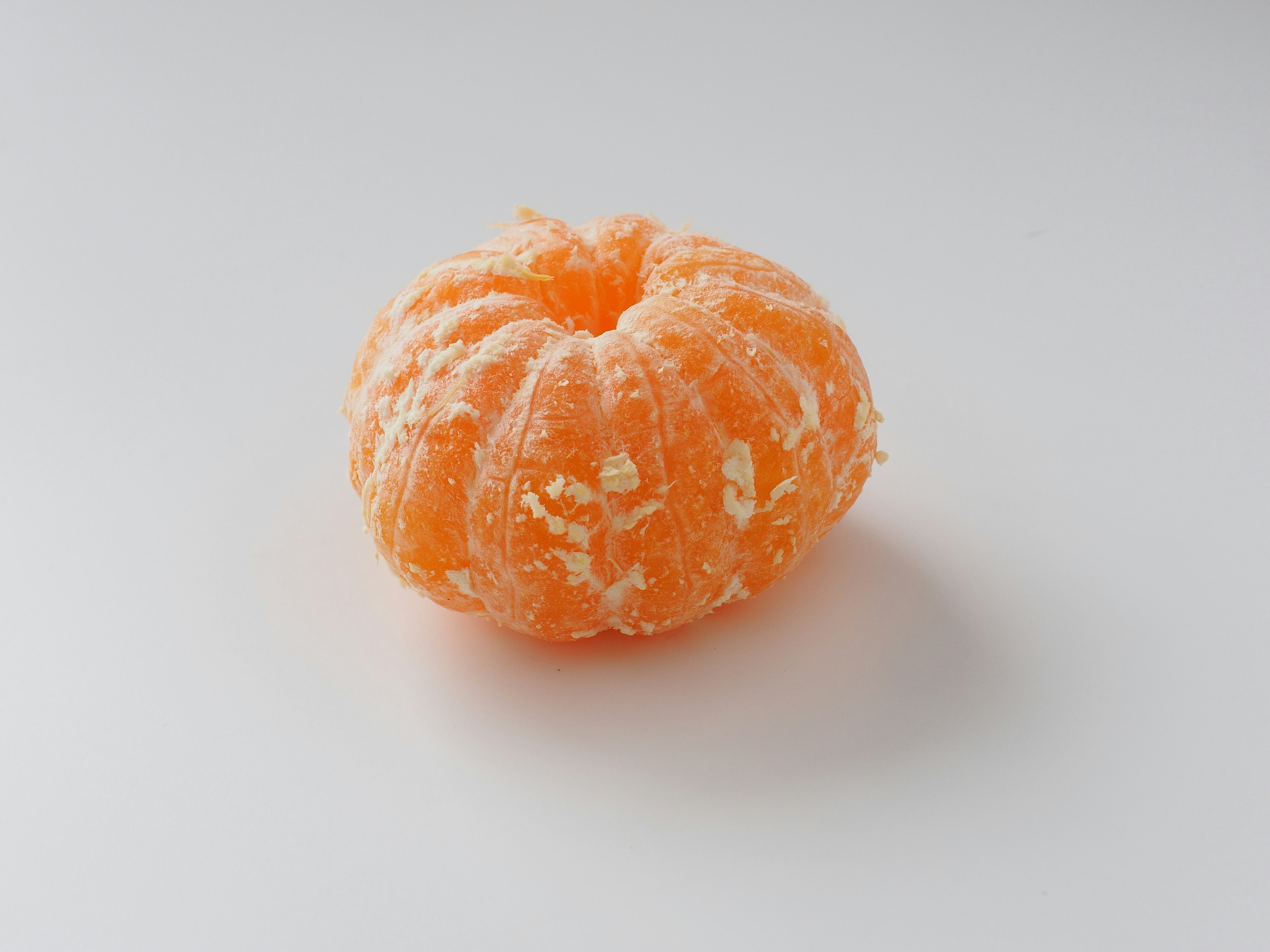 Une petite citrouille orange placée sur un fond blanc