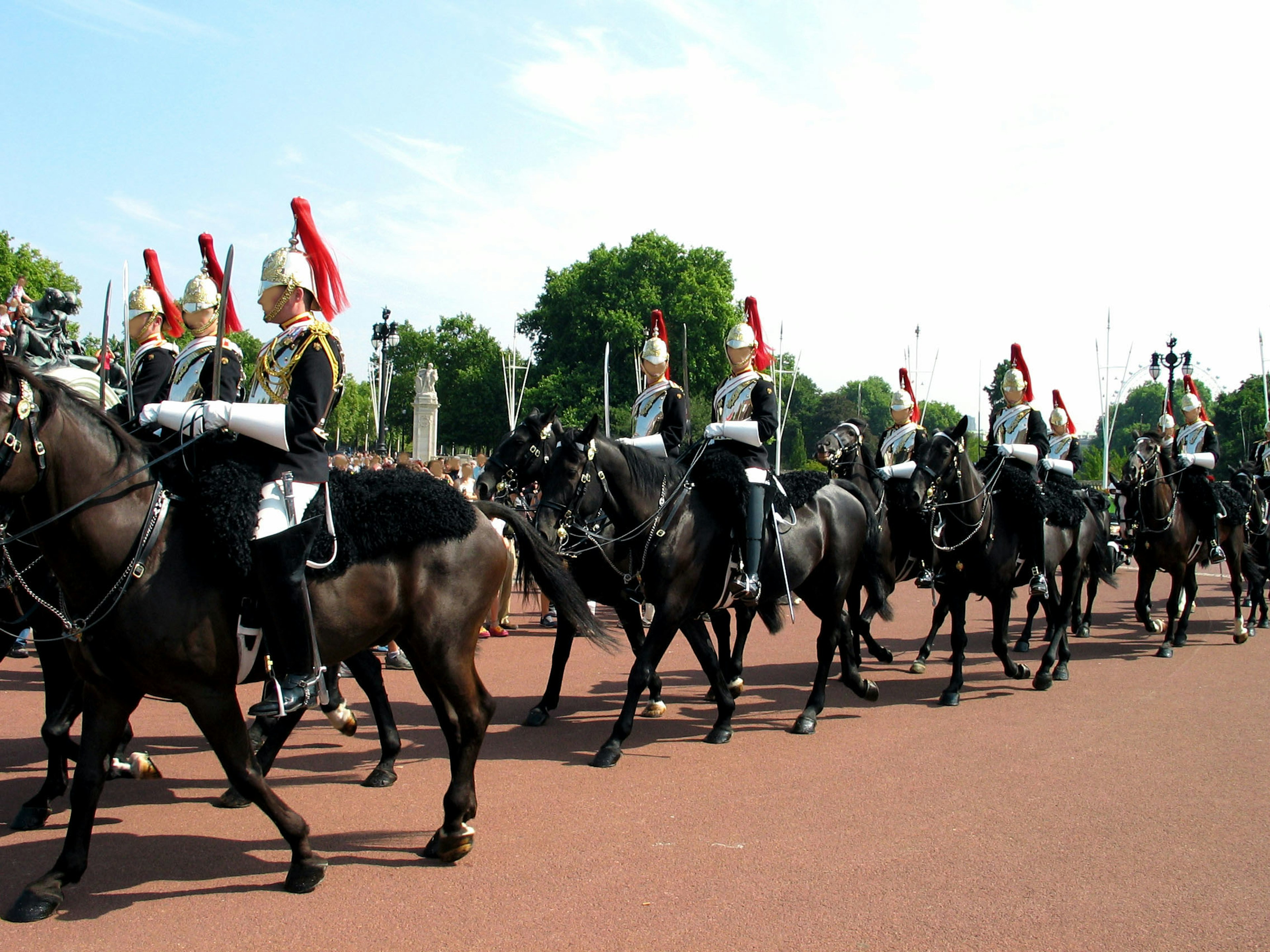 Guardias marchando sobre caballos negros con cascos de plumas rojas