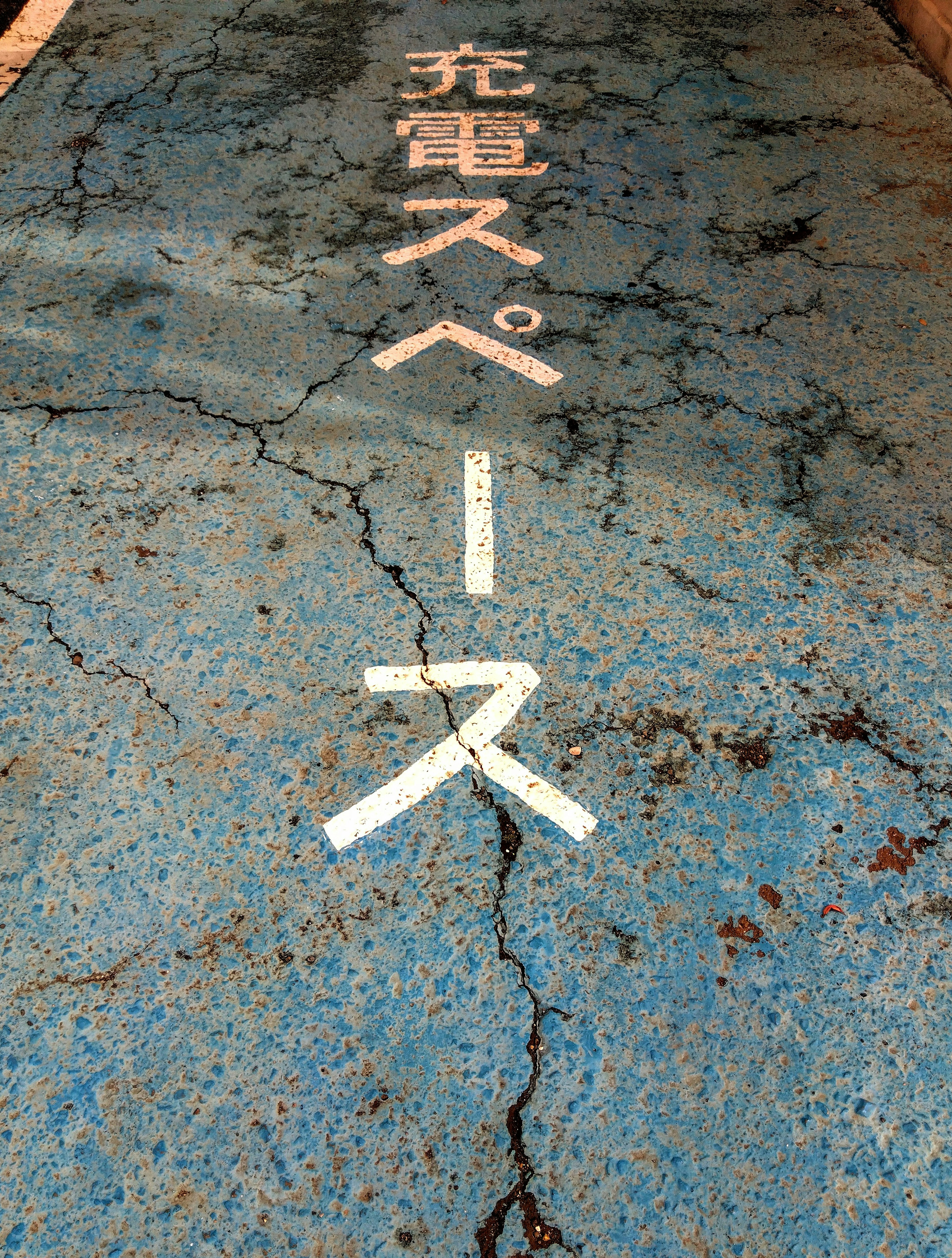 Blue pavement with text indicating charging space