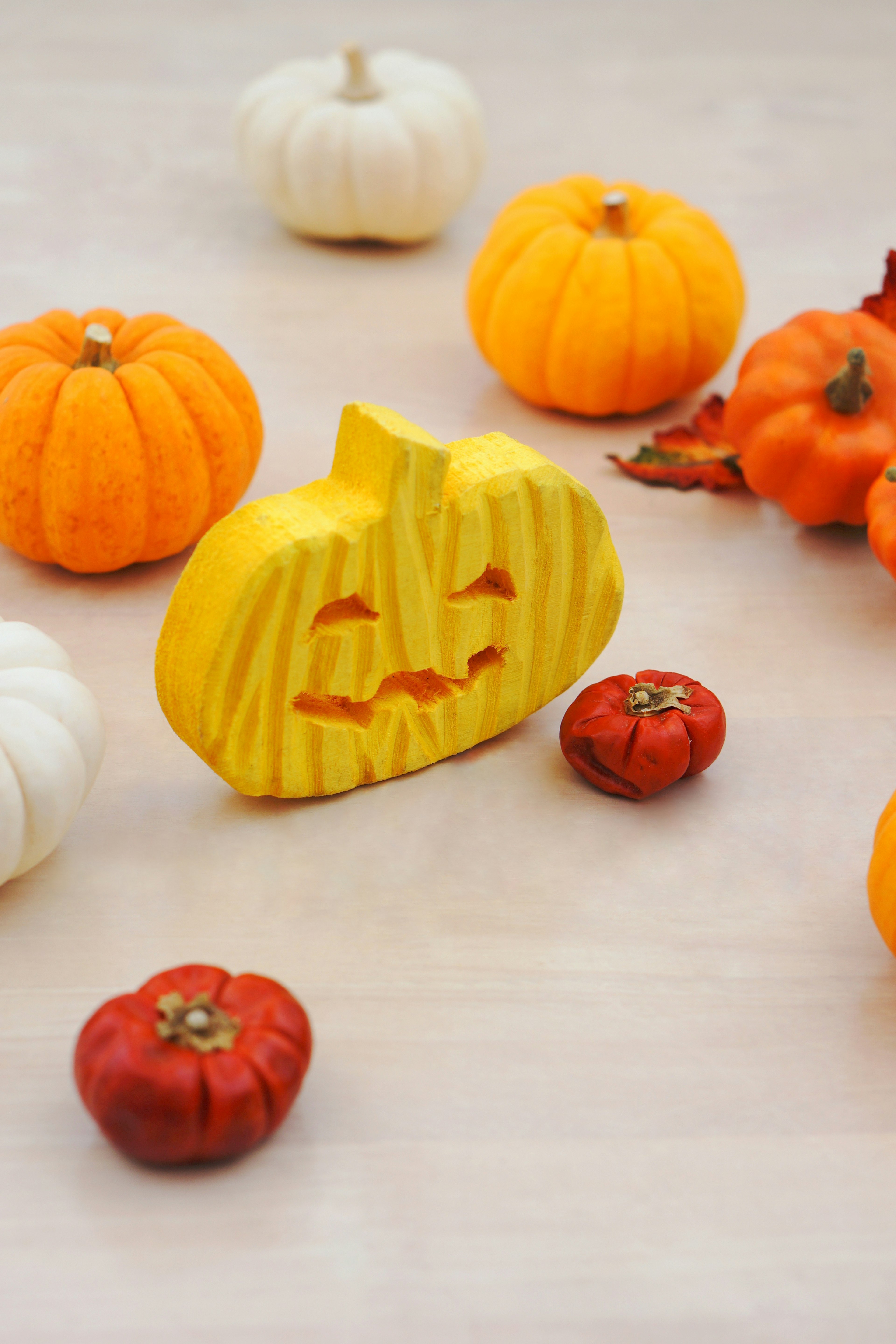 Yellow carved pumpkin with a smiling face surrounded by various pumpkins