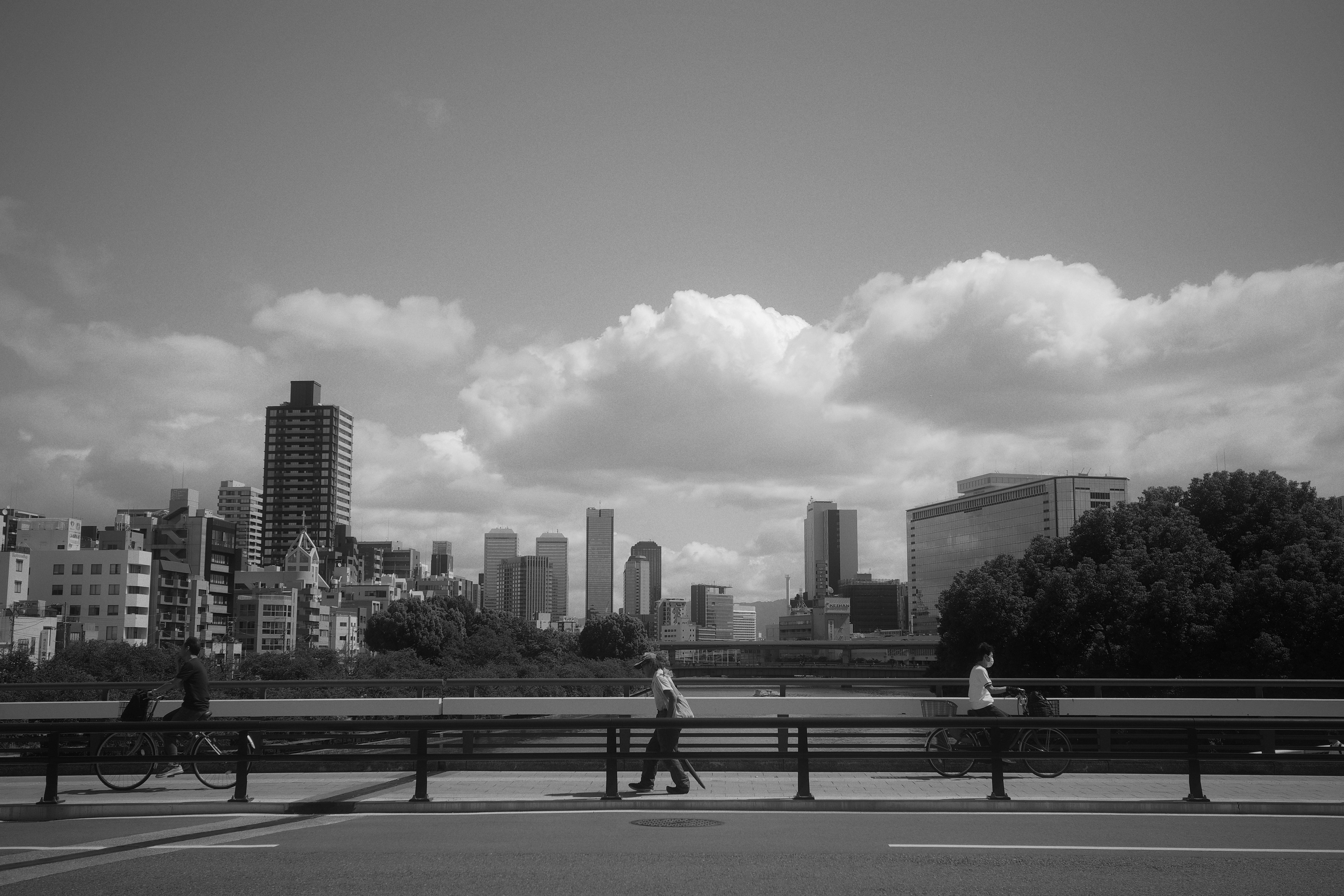 Paisaje urbano en blanco y negro con personas caminando y nubes en el cielo