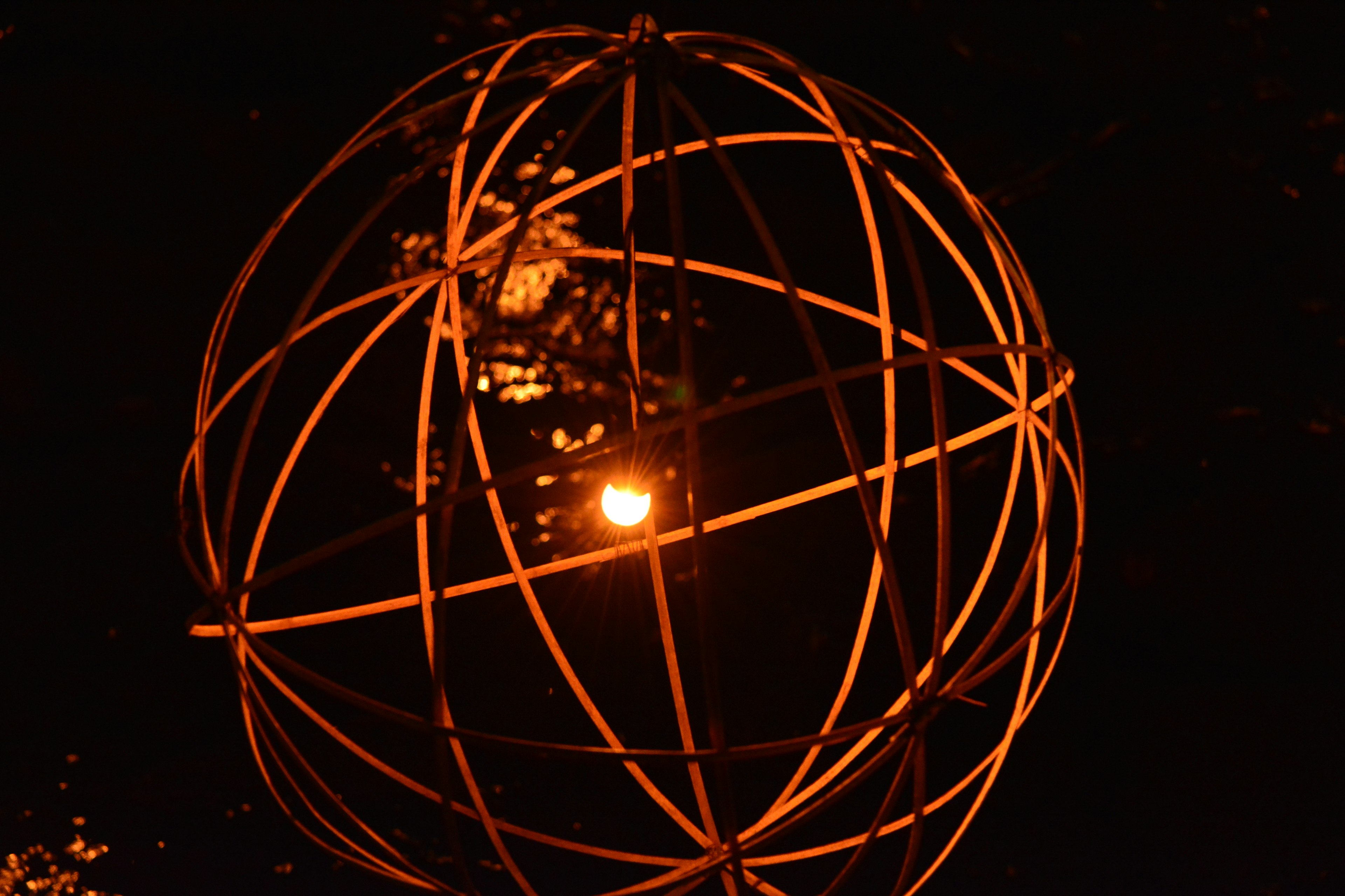 Orange spherical art installation glowing at night