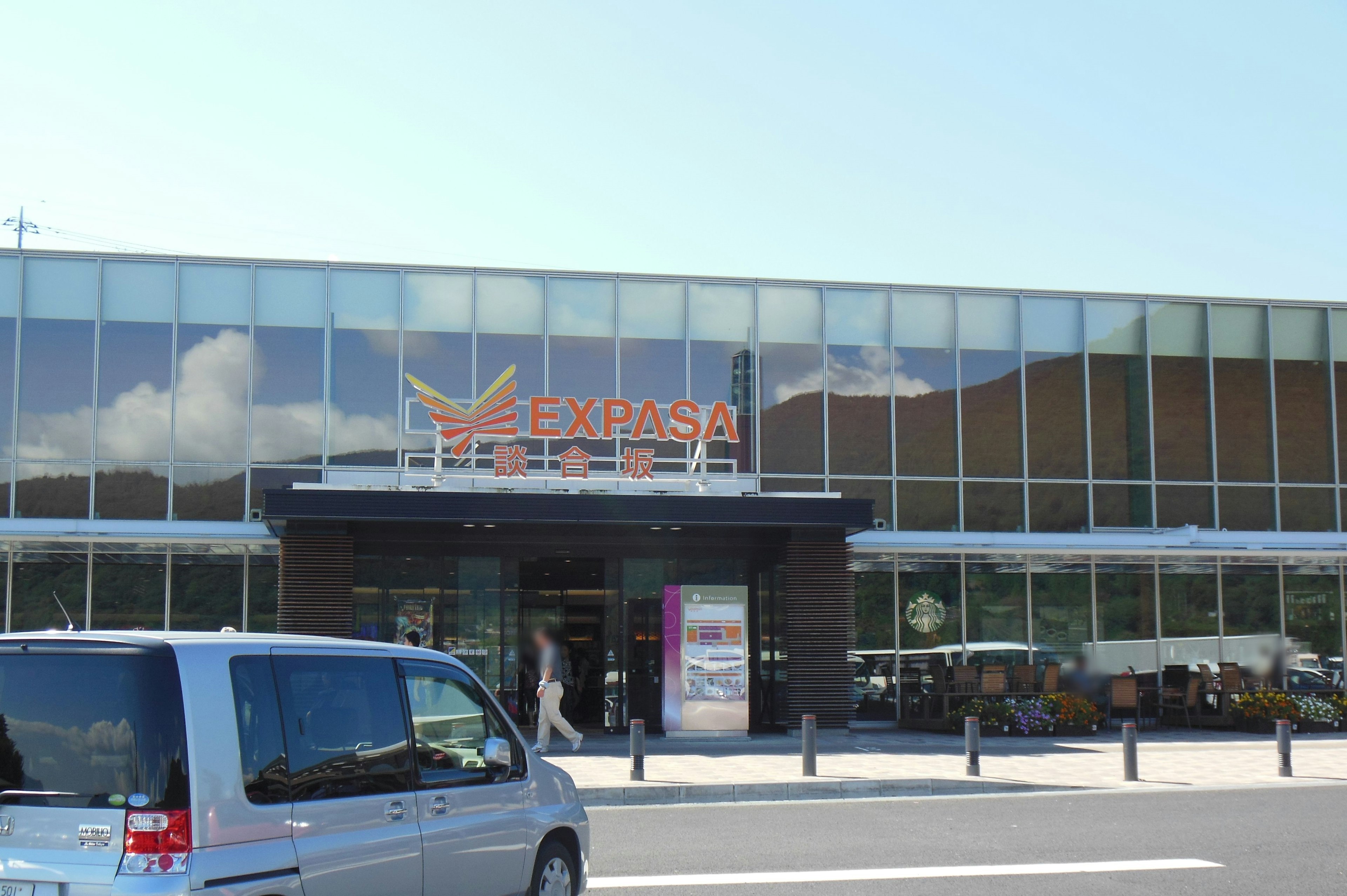 Modern exterior of Ekiparesa Hotel under a bright sky with a car parked in front