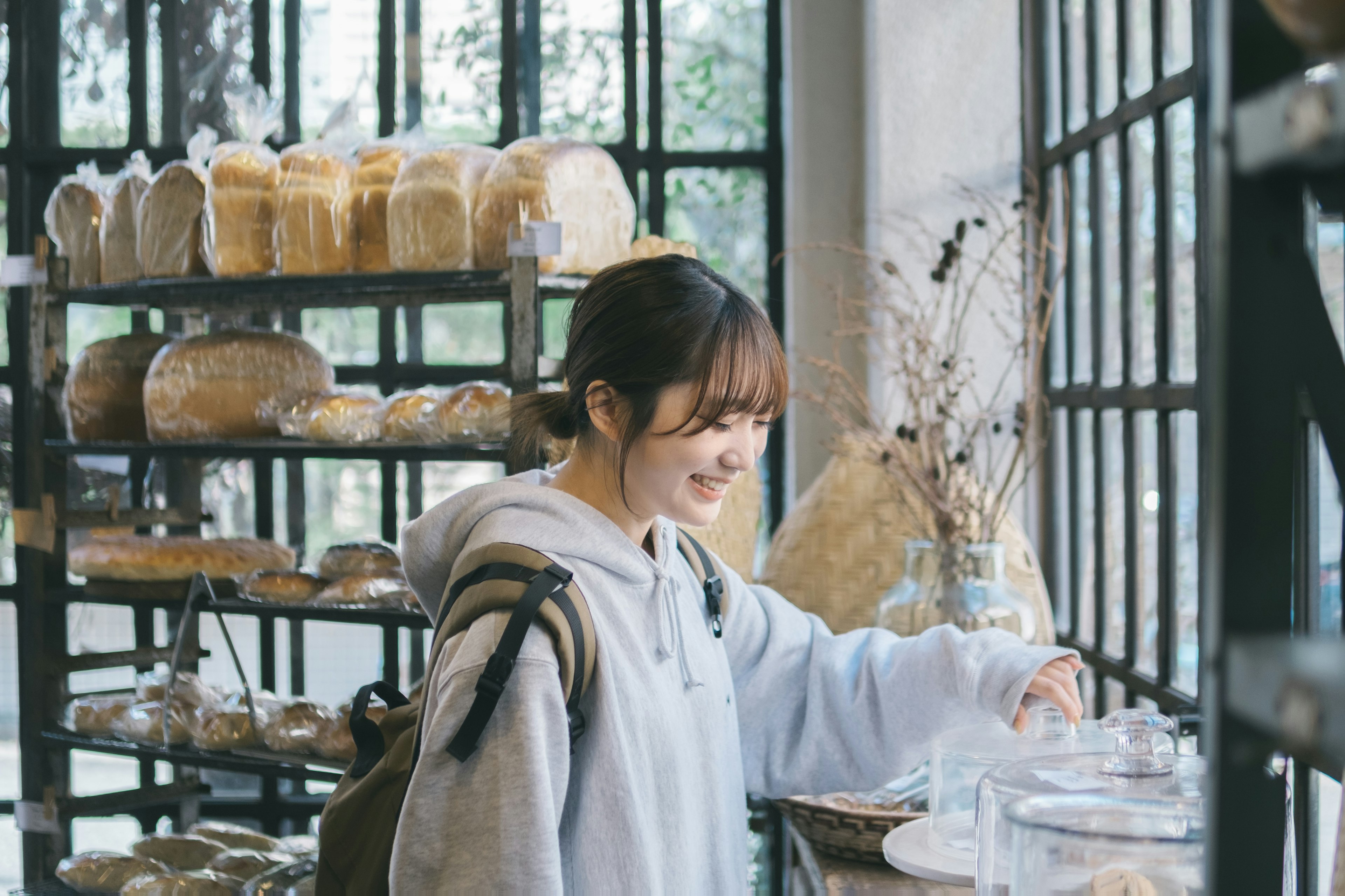 女性がパンの棚の前で微笑んでいるカフェの内部